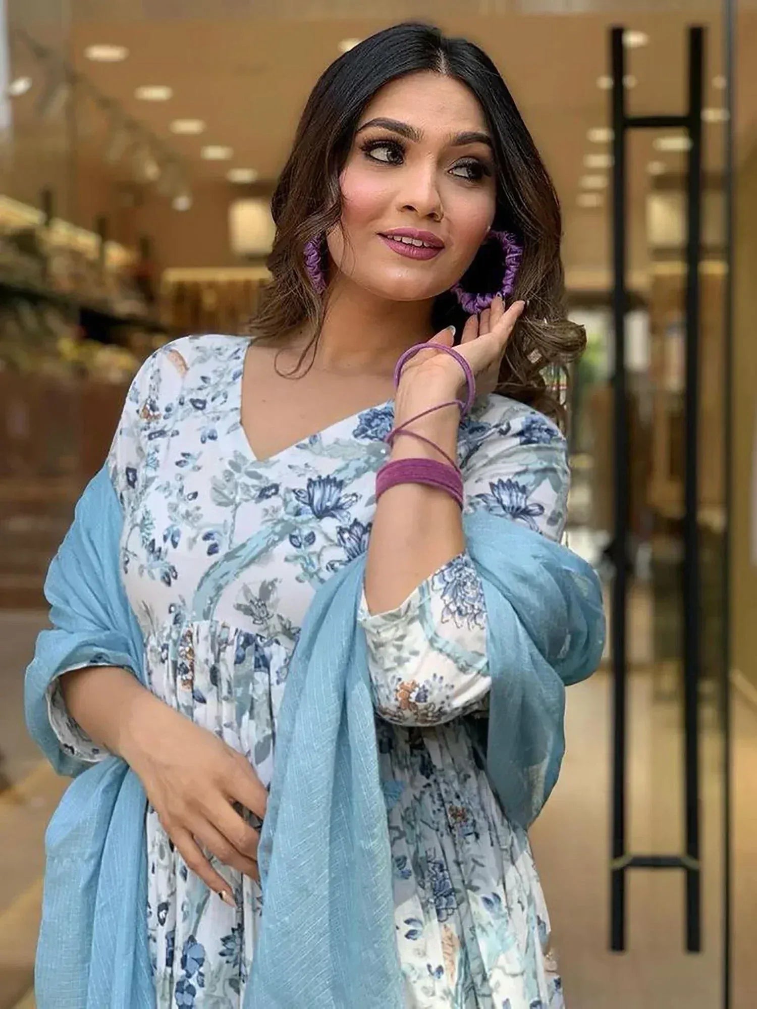 Woman in floral print ethnic kurta with blue dupatta, purple accessories, stylish Indian wear