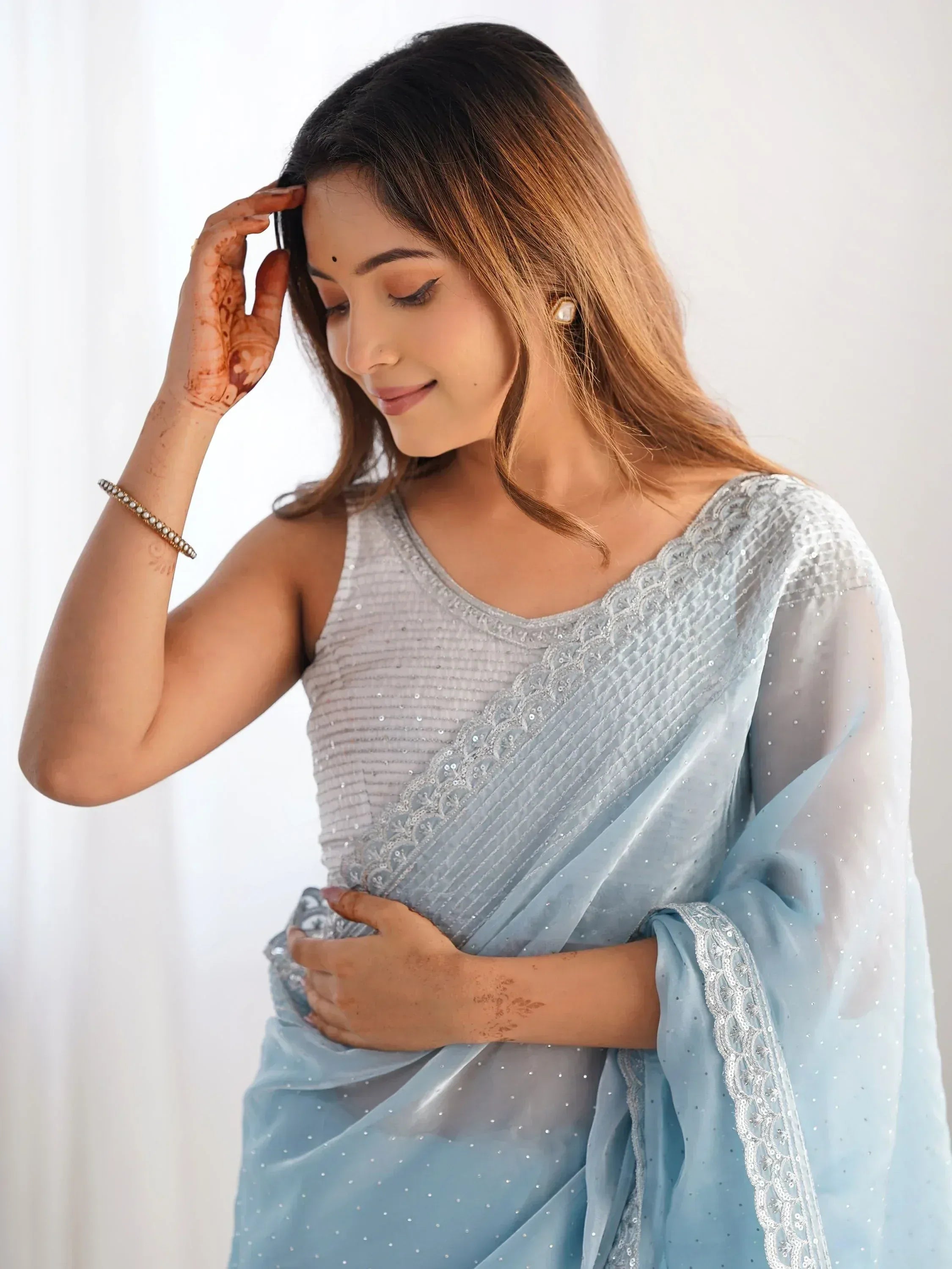 Elegant light blue ethnic saree with sequin work and henna designs, perfect for Indian occasions.