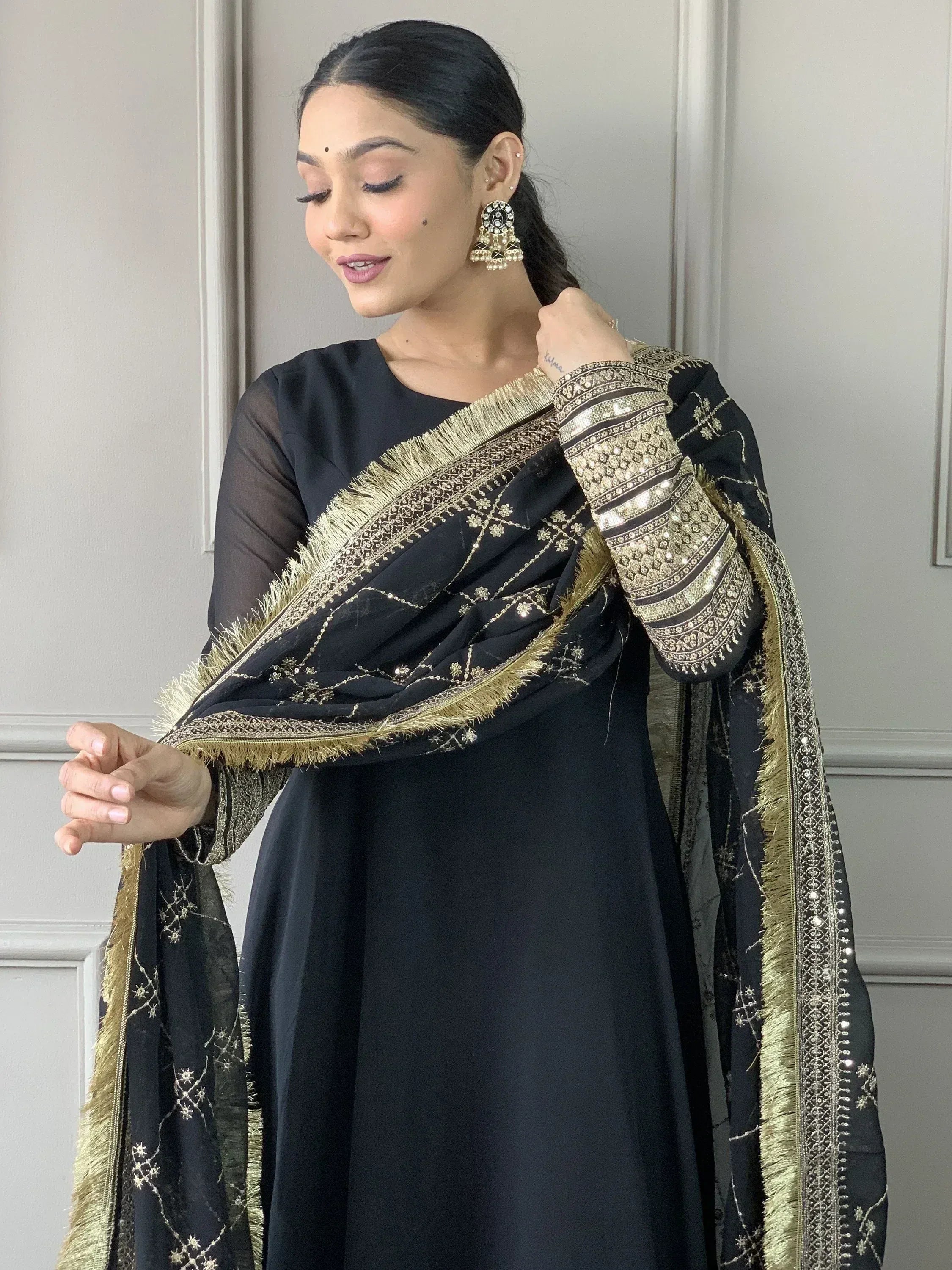 Black Indian ethnic salwar kameez with gold embroidery and fringe dupatta, perfect for festive occasions.