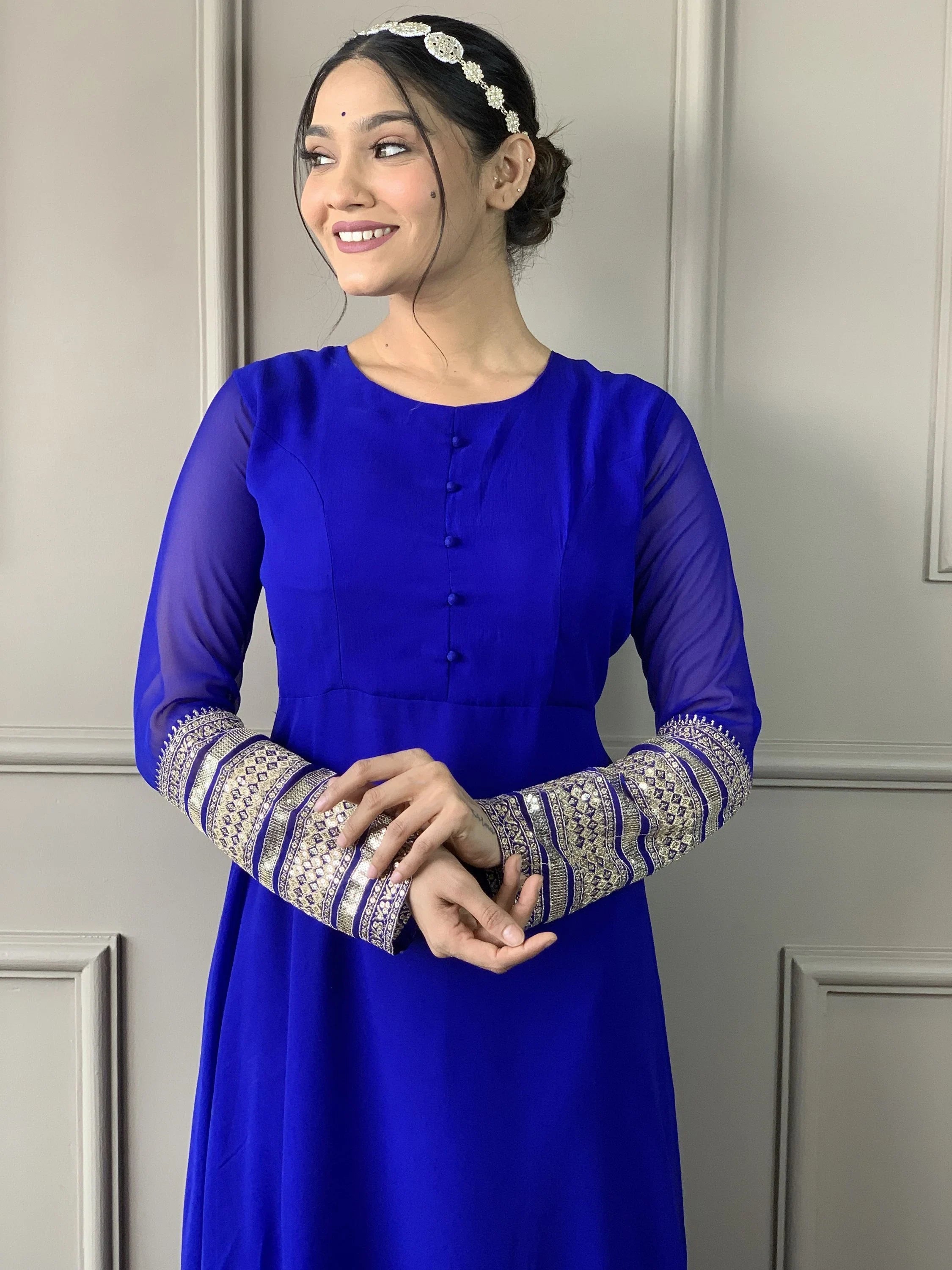 Woman in royal blue ethnic gown with sheer sleeves and gold embroidered cuffs