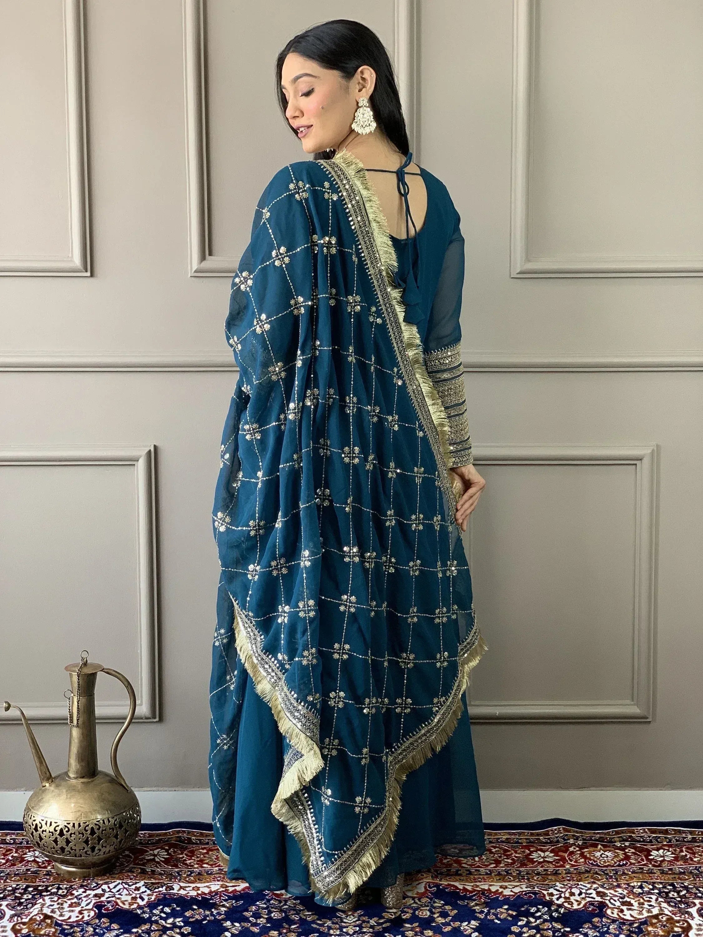 Teal blue ethnic salwar kameez with gold embroidery and fringe, perfect for Indian weddings or festive occasions.