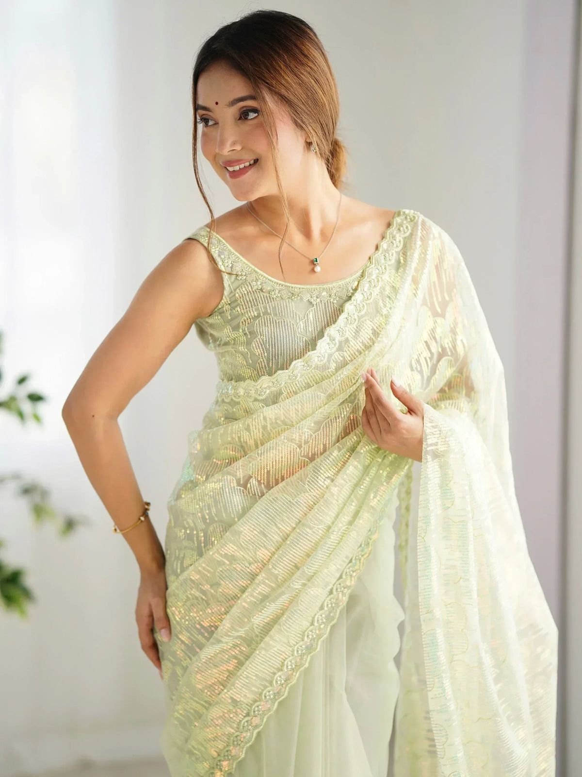 Woman in elegant light green embroidered saree with sequins, perfect for Indian ethnic occasions