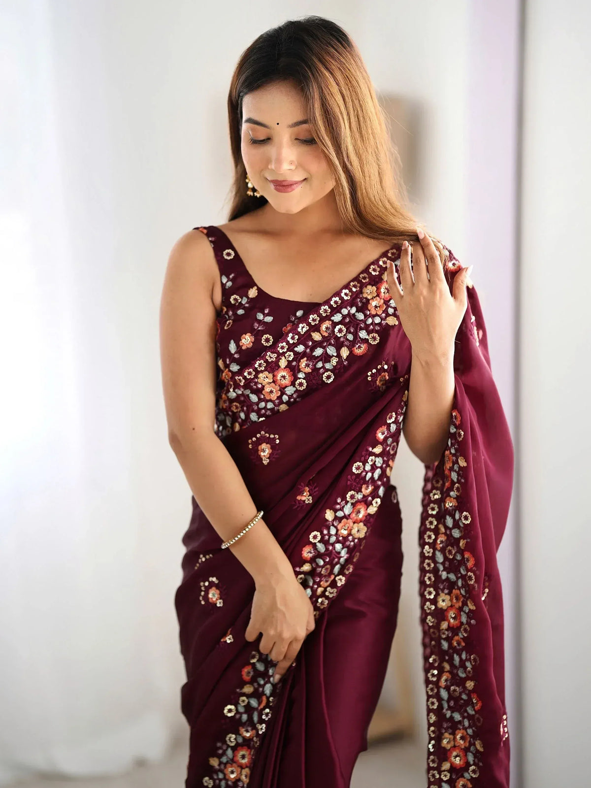 Woman in maroon floral embroidered saree with sequin detailing, elegant Indian ethnic wear