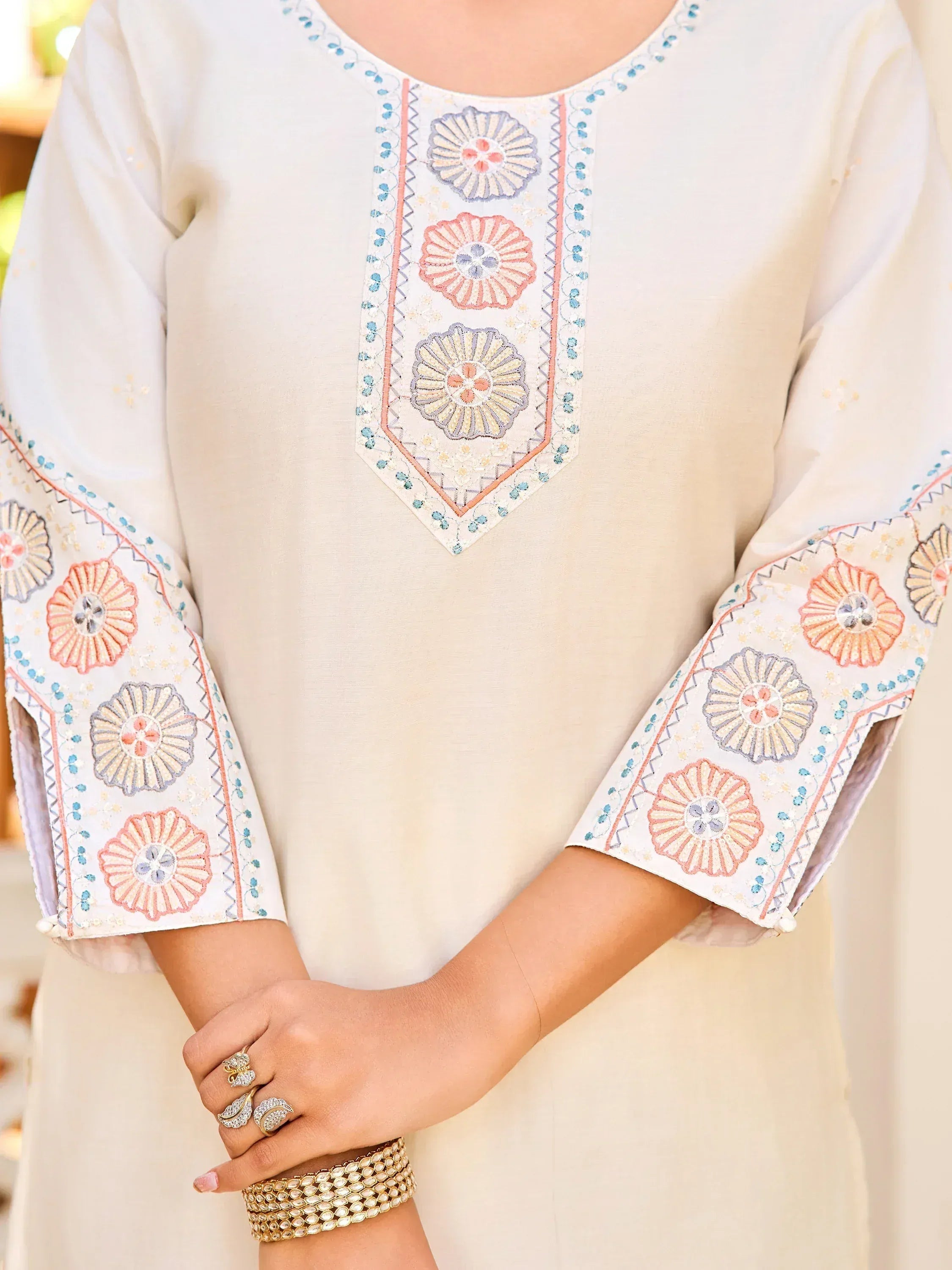 Cream ethnic kurti with floral embroidery on neckline and sleeves, paired with traditional jewelry