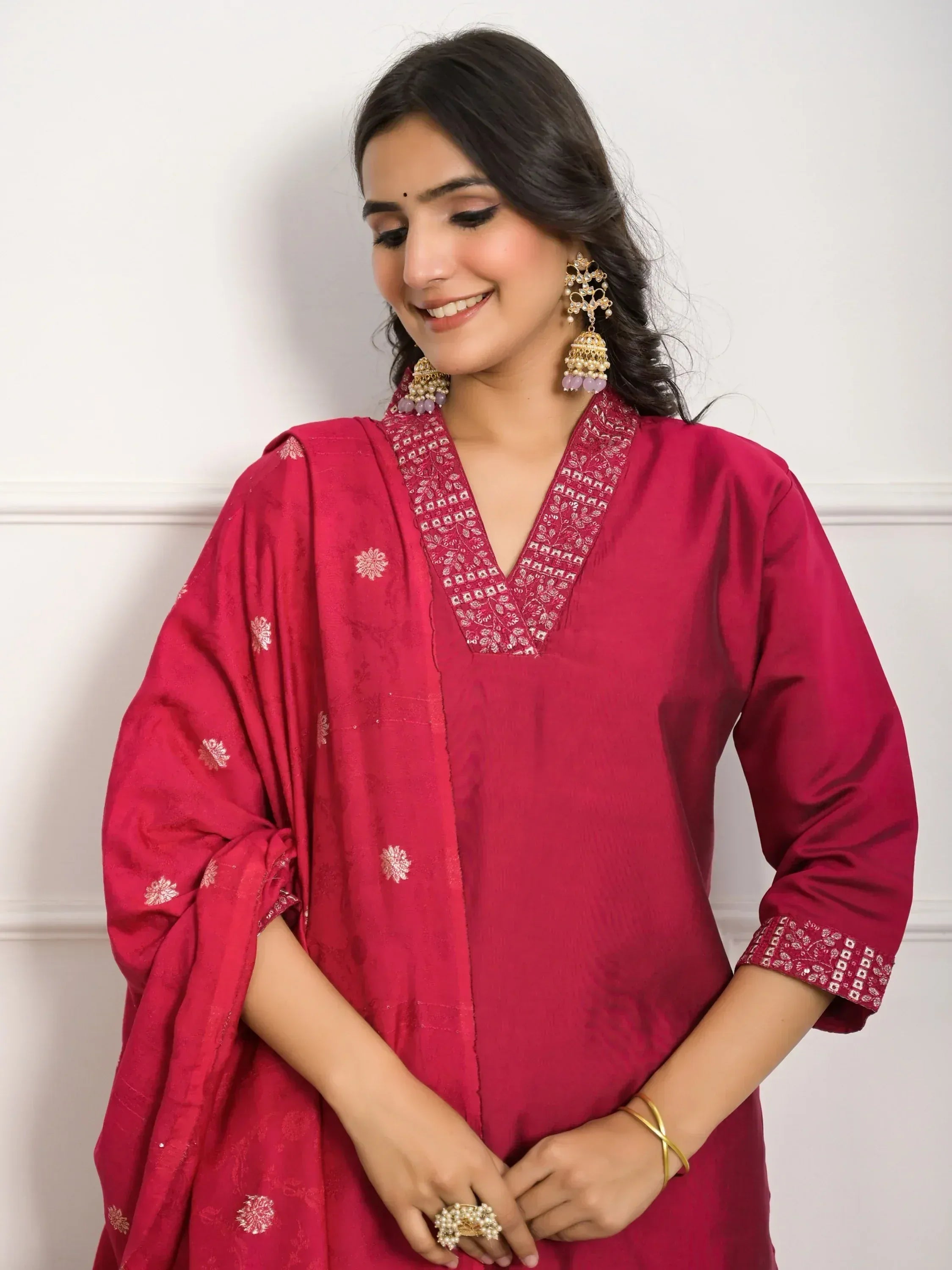 Woman in maroon ethnic kurta with gold embroidery, matching dupatta, and jhumka earrings