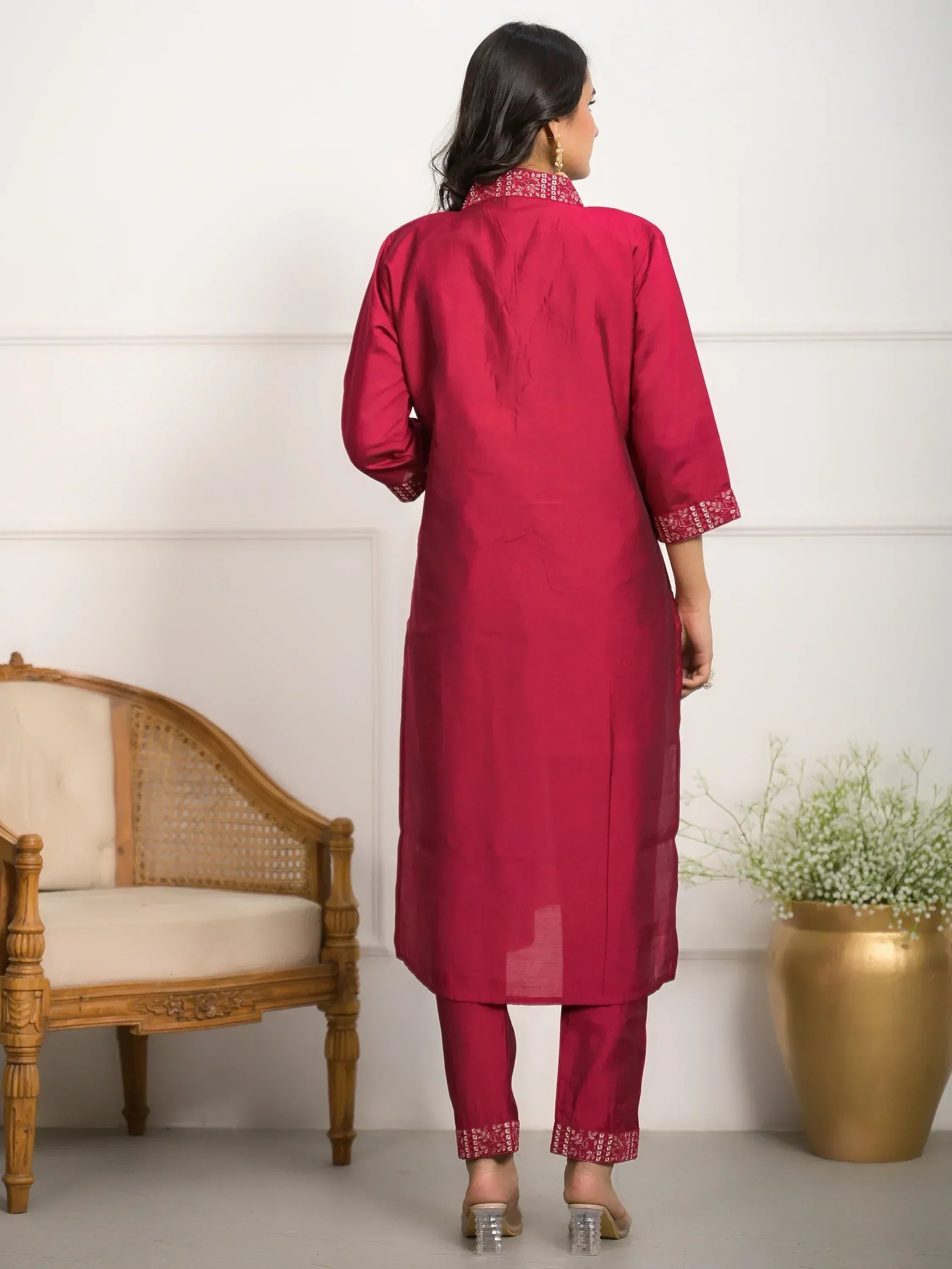 Woman in maroon ethnic kurta set with embroidered cuffs and collar, paired with matching pants for traditional Indian wear