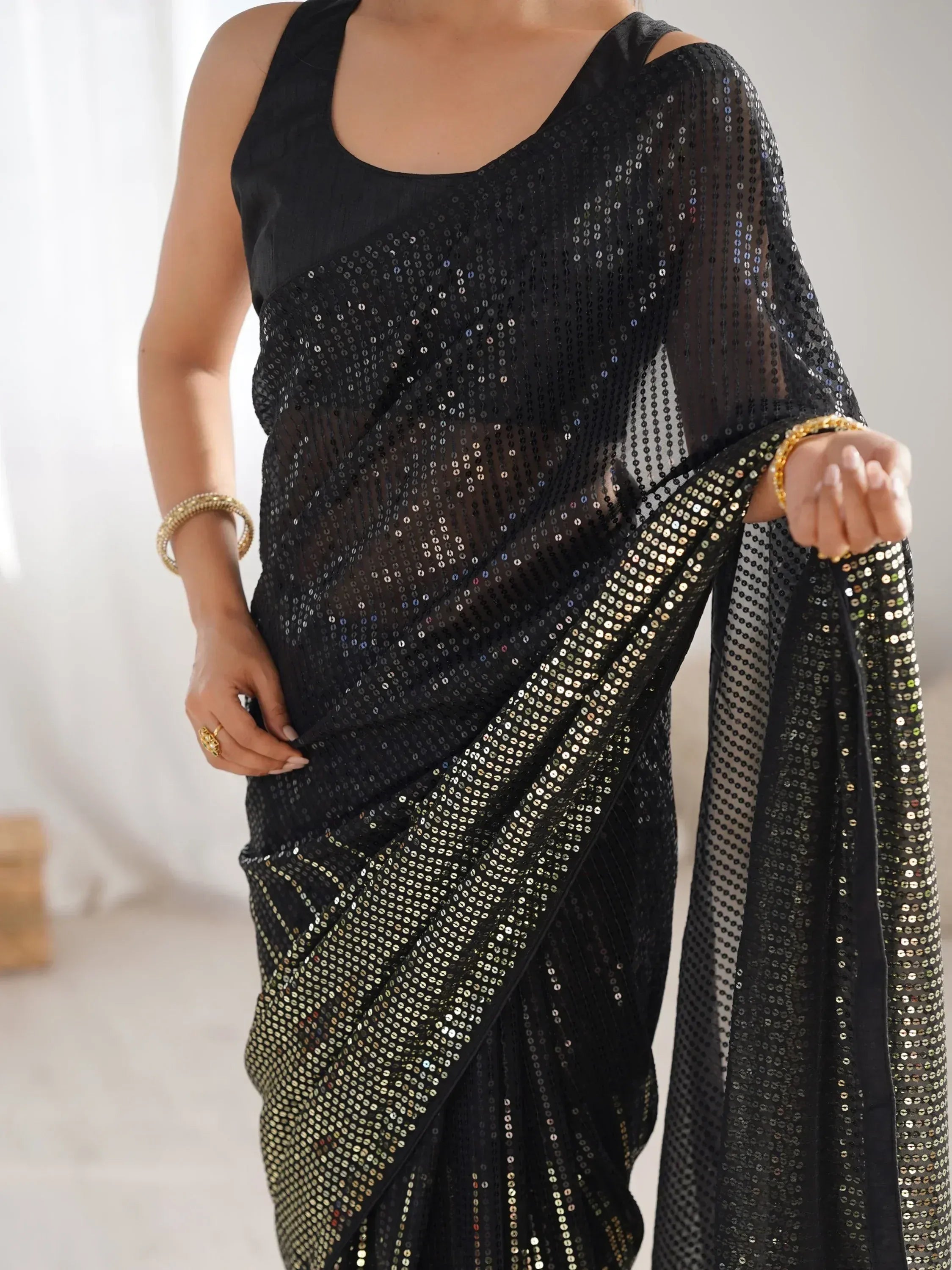 Black sequin saree with sheer overlay and gold accents, styled with sleeveless blouse for ethnic wear
