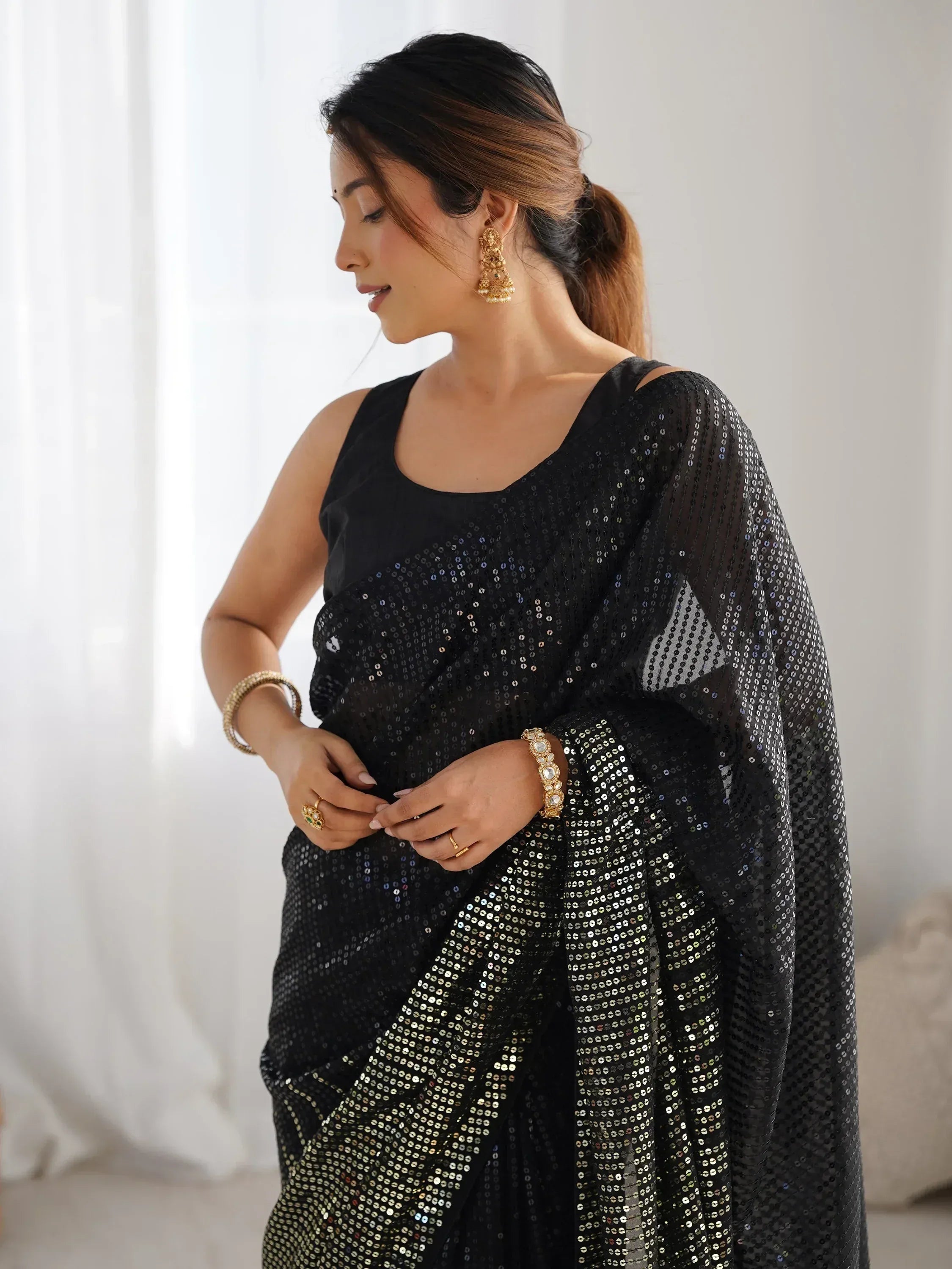 Black sequin saree with sheer cape, styled with gold jewelry for Indian ethnic wear