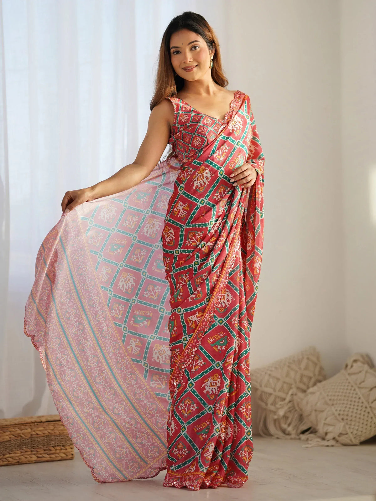 Woman in vibrant red and pink printed saree with ethnic motifs, showcasing traditional Indian wear