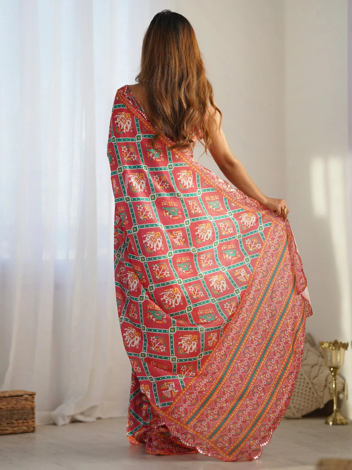 Woman in red ethnic gown with green and gold block print patterns, back view