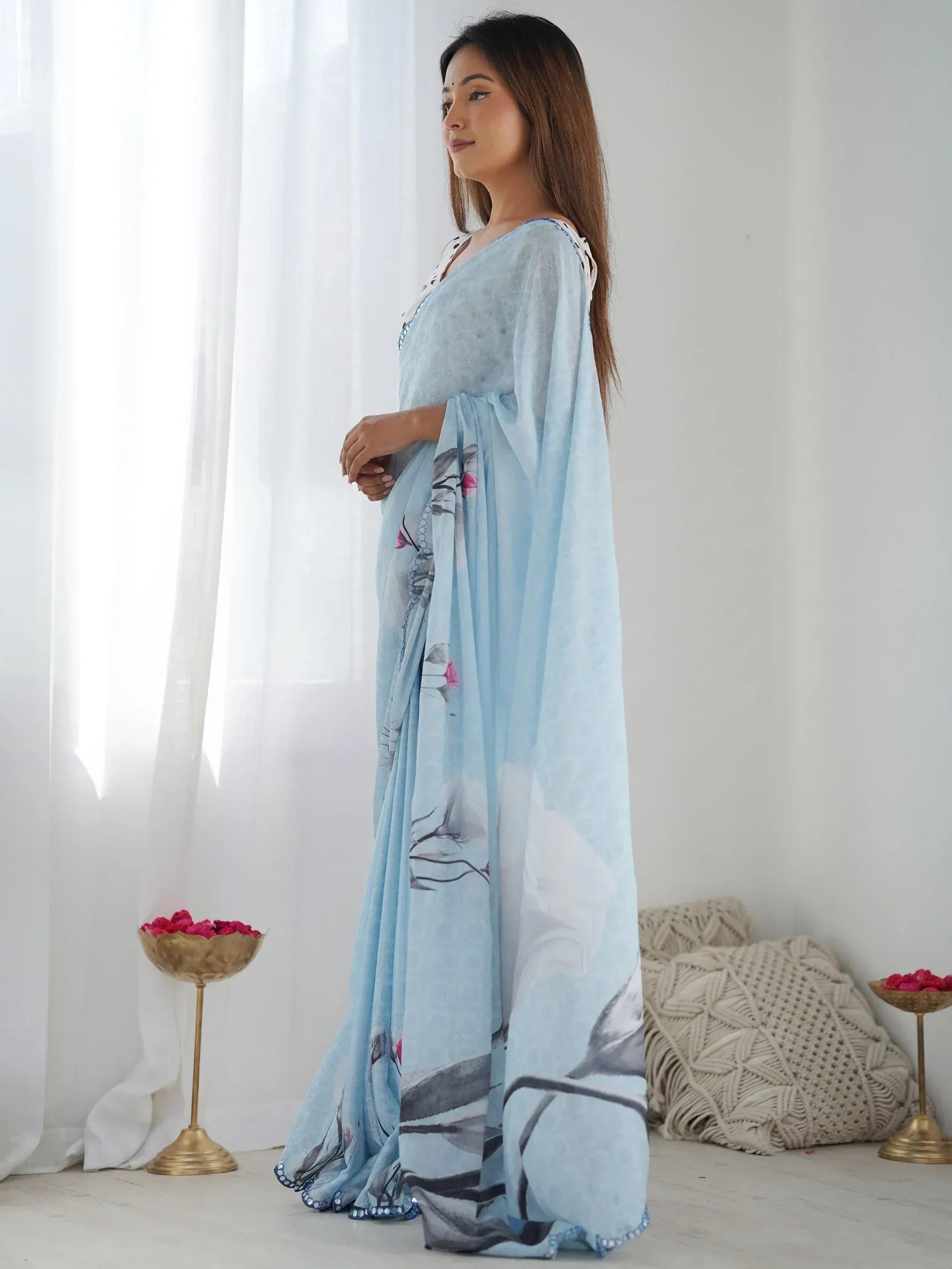 Woman in light blue floral printed saree with embroidered border, elegant ethnic wear for special occasions