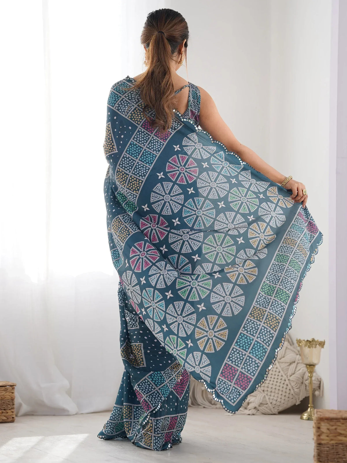 Woman in teal printed saree with geometric patterns and mirror work, showcasing ethnic Indian wear