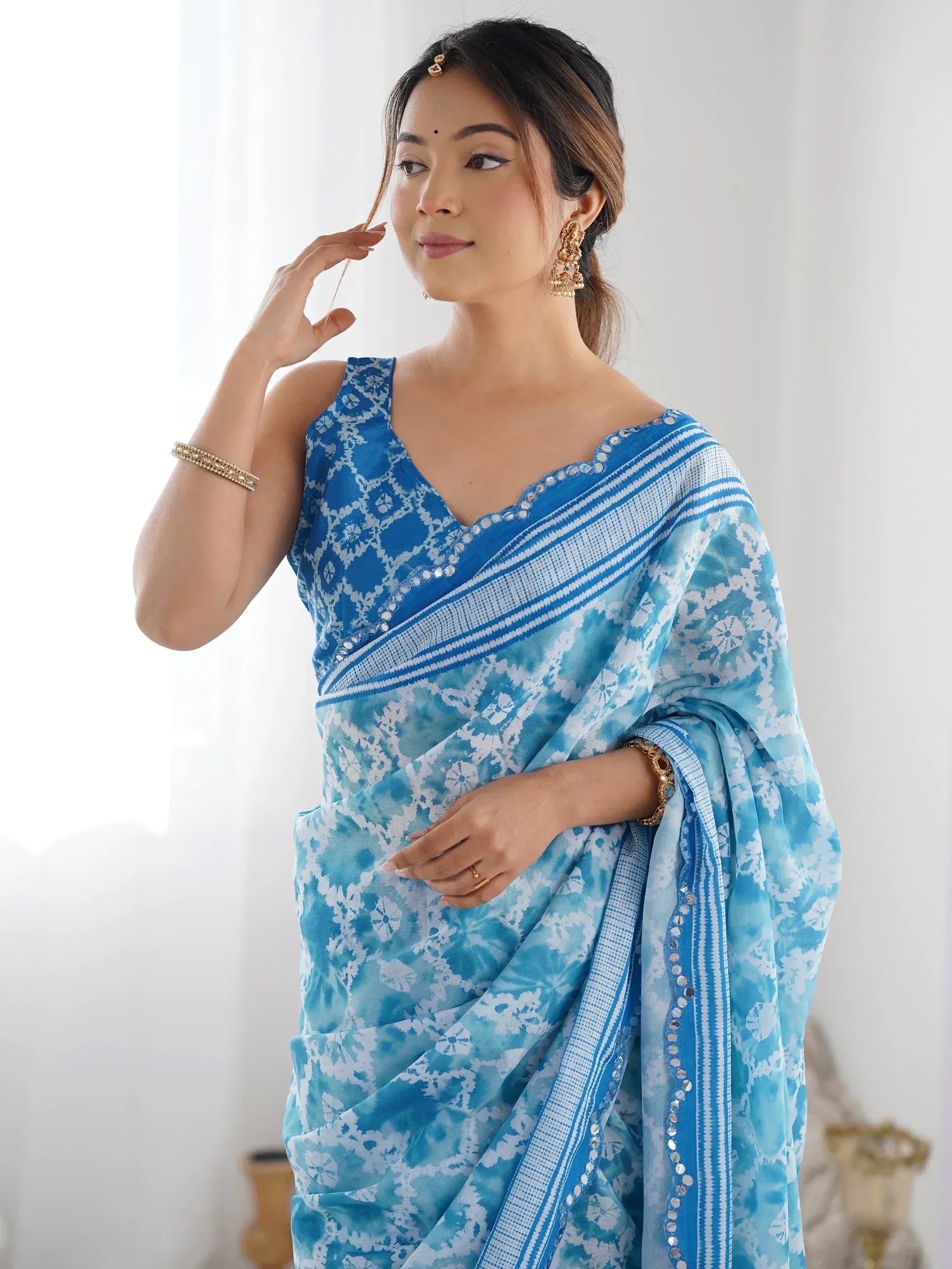 Blue and white floral print saree with mirror work, styled with gold jewelry for Indian ethnic wear