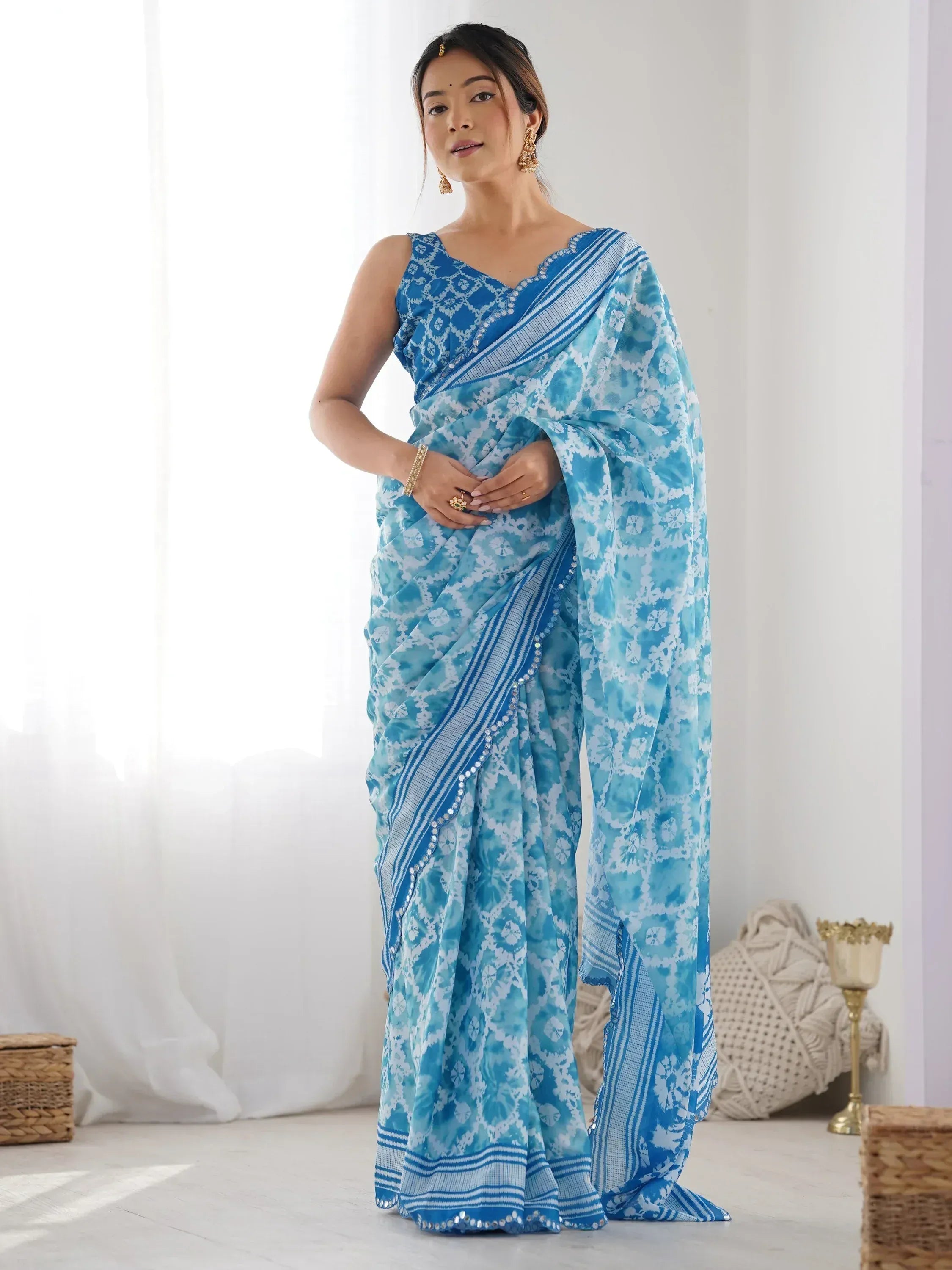 Blue and white floral print saree with sequin border, styled with gold jewelry for ethnic wear