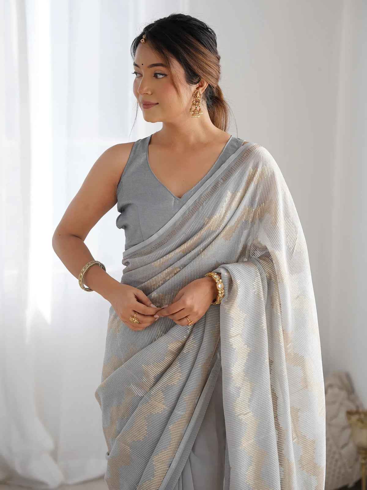 Grey saree with gold sequin work, styled with traditional jewelry for ethnic occasions