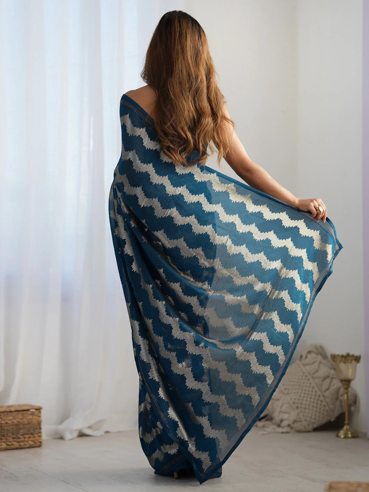 Woman in blue and white patterned saree, showcasing elegant ethnic wear with geometric design.