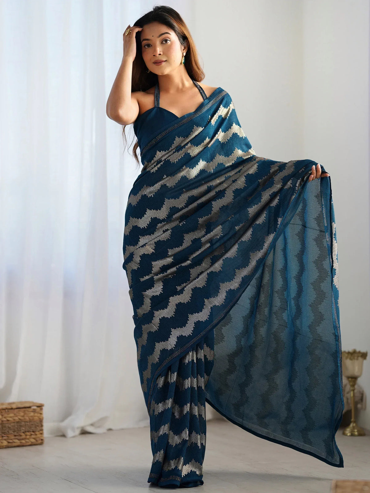 Woman in elegant blue saree with silver geometric pattern, styled with halter neck blouse for ethnic wear.