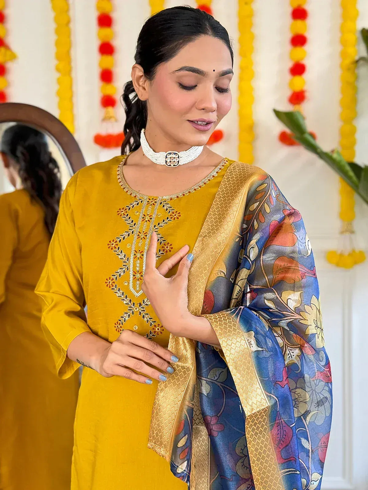 Woman in colorful striped ethnic saree with yellow, pink, green, and blue hues, festive decor background