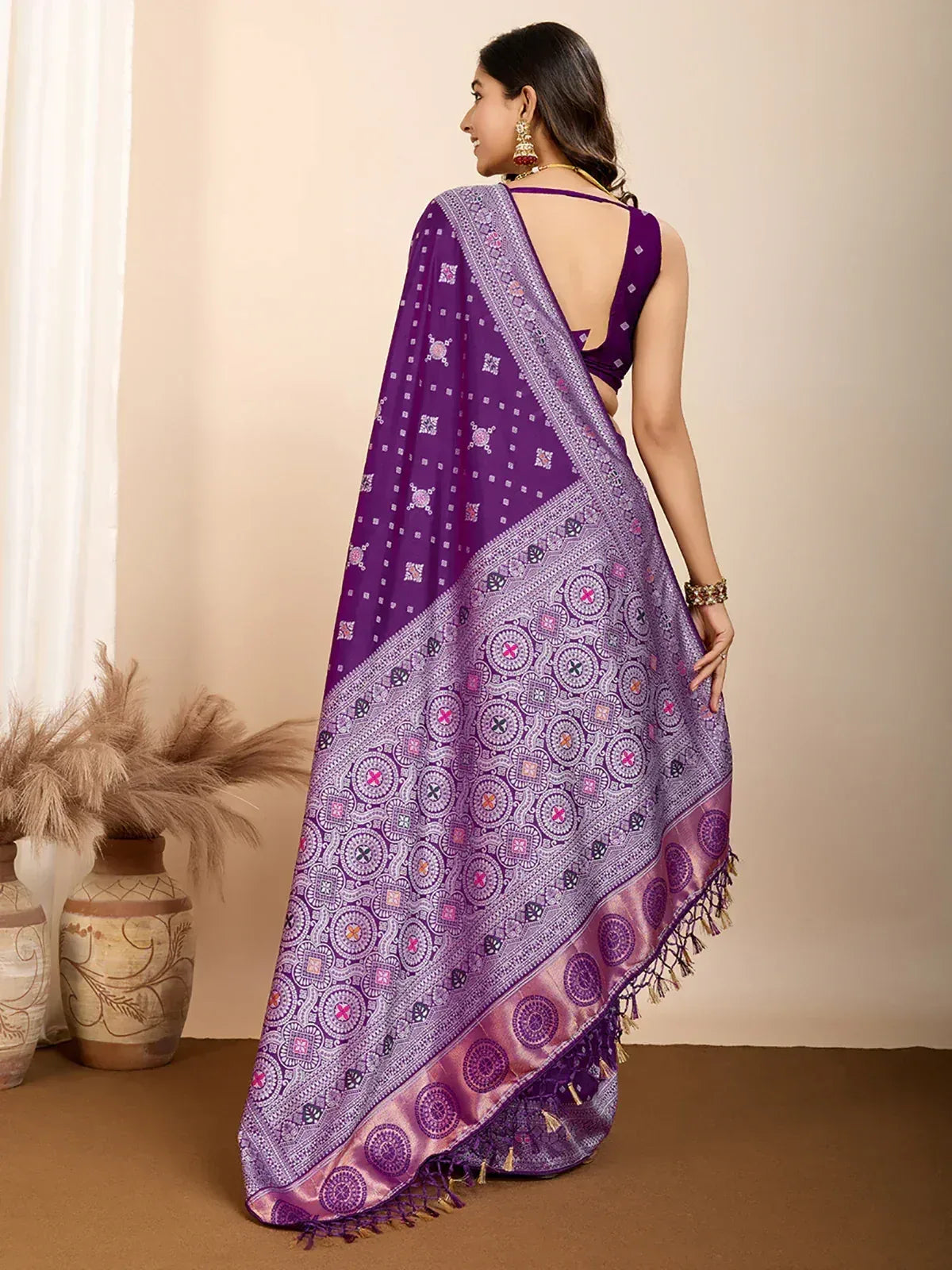 Purple ethnic saree with intricate circular patterns and tassels, paired with a backless blouse