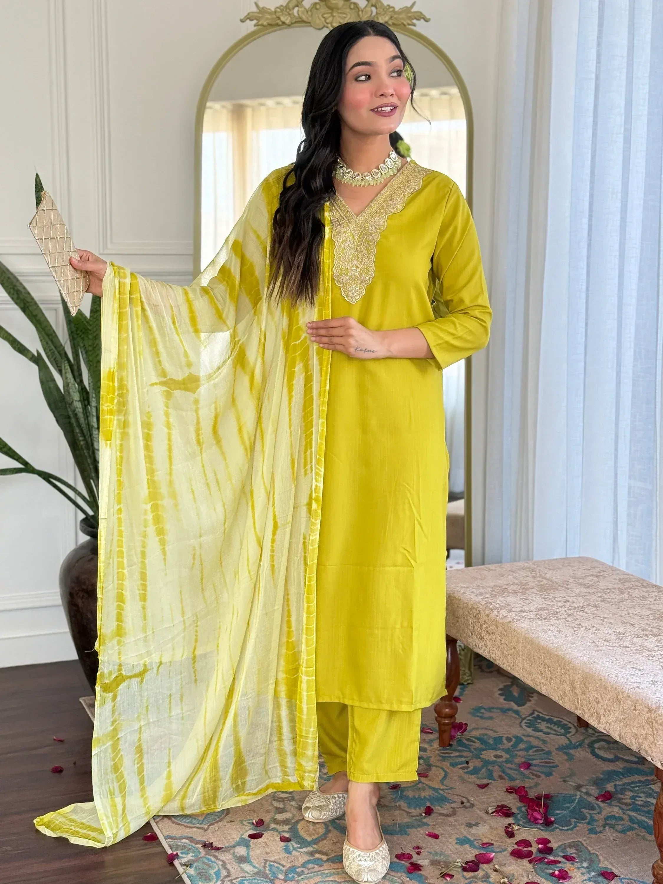 Yellow ethnic salwar kameez with gold embroidery, tie-dye dupatta, and matching jewelry for festive occasions
