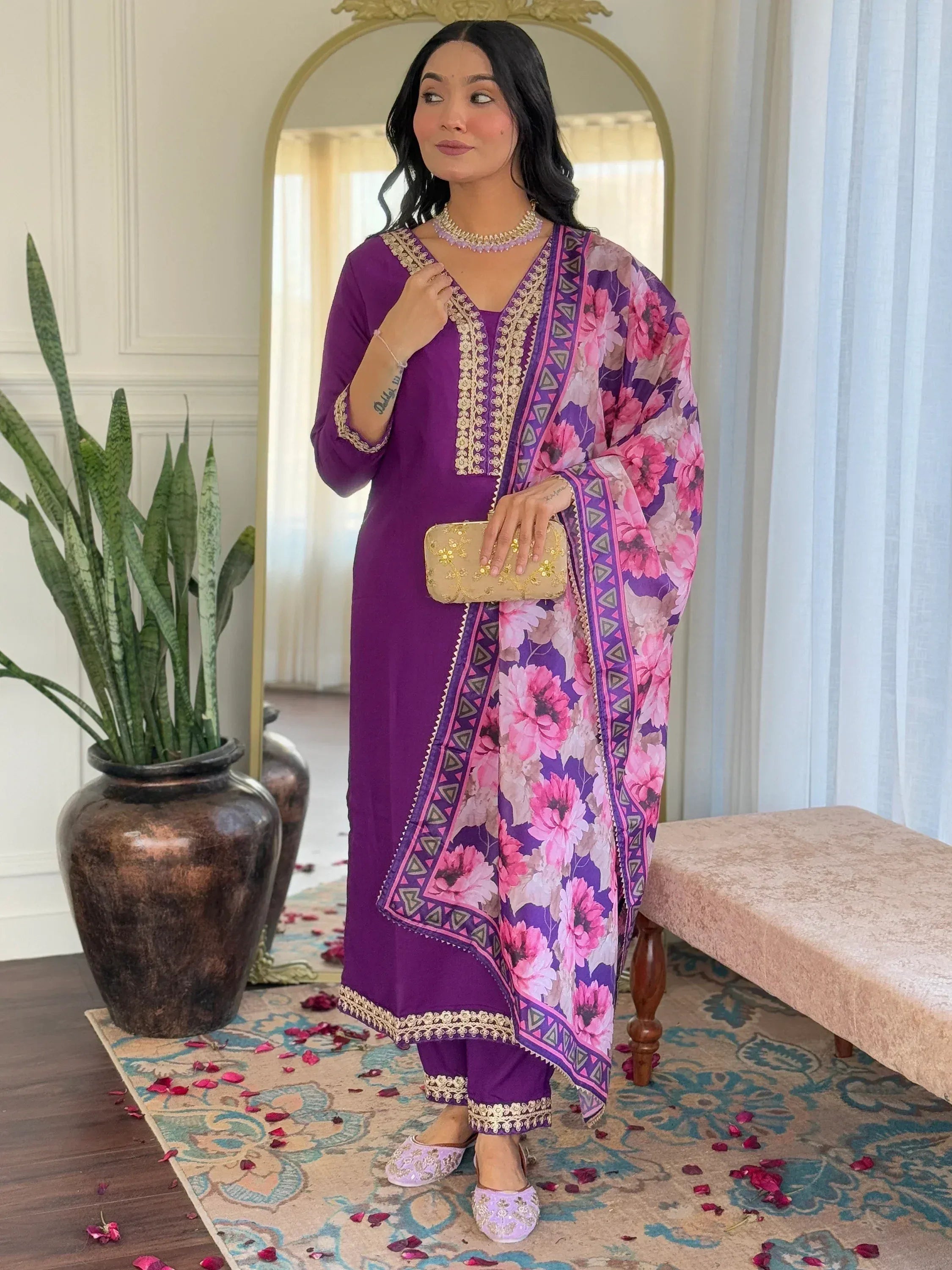 Purple ethnic salwar kameez with floral dupatta and gold embroidery, styled with clutch and juttis