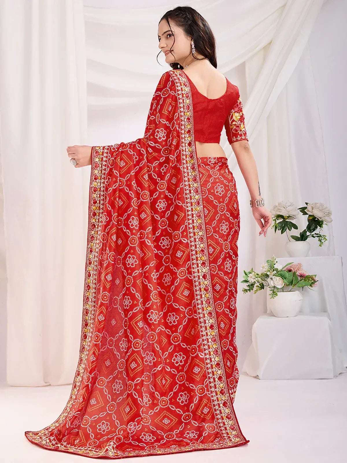 Red printed saree with floral motifs and embroidered border, paired with matching blouse for ethnic wear