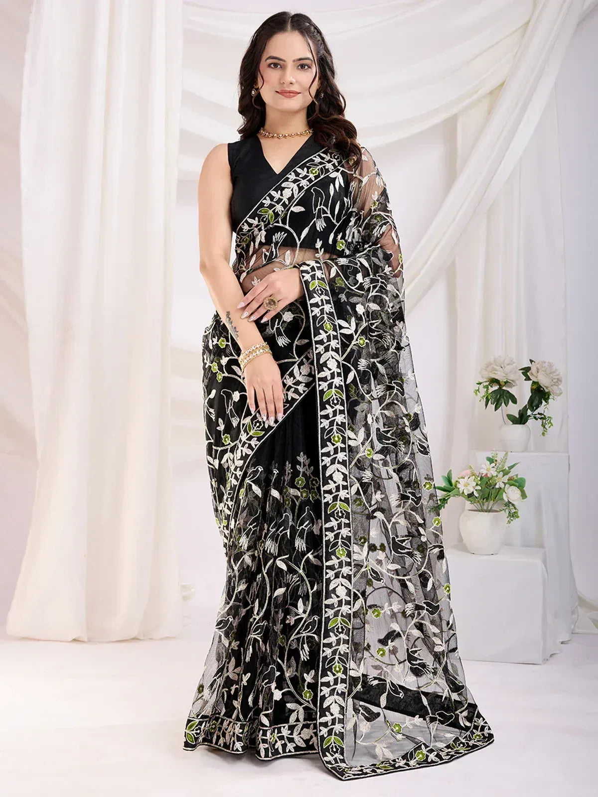 Black embroidered saree with white and green floral design, paired with sleeveless blouse, ideal for ethnic occasions