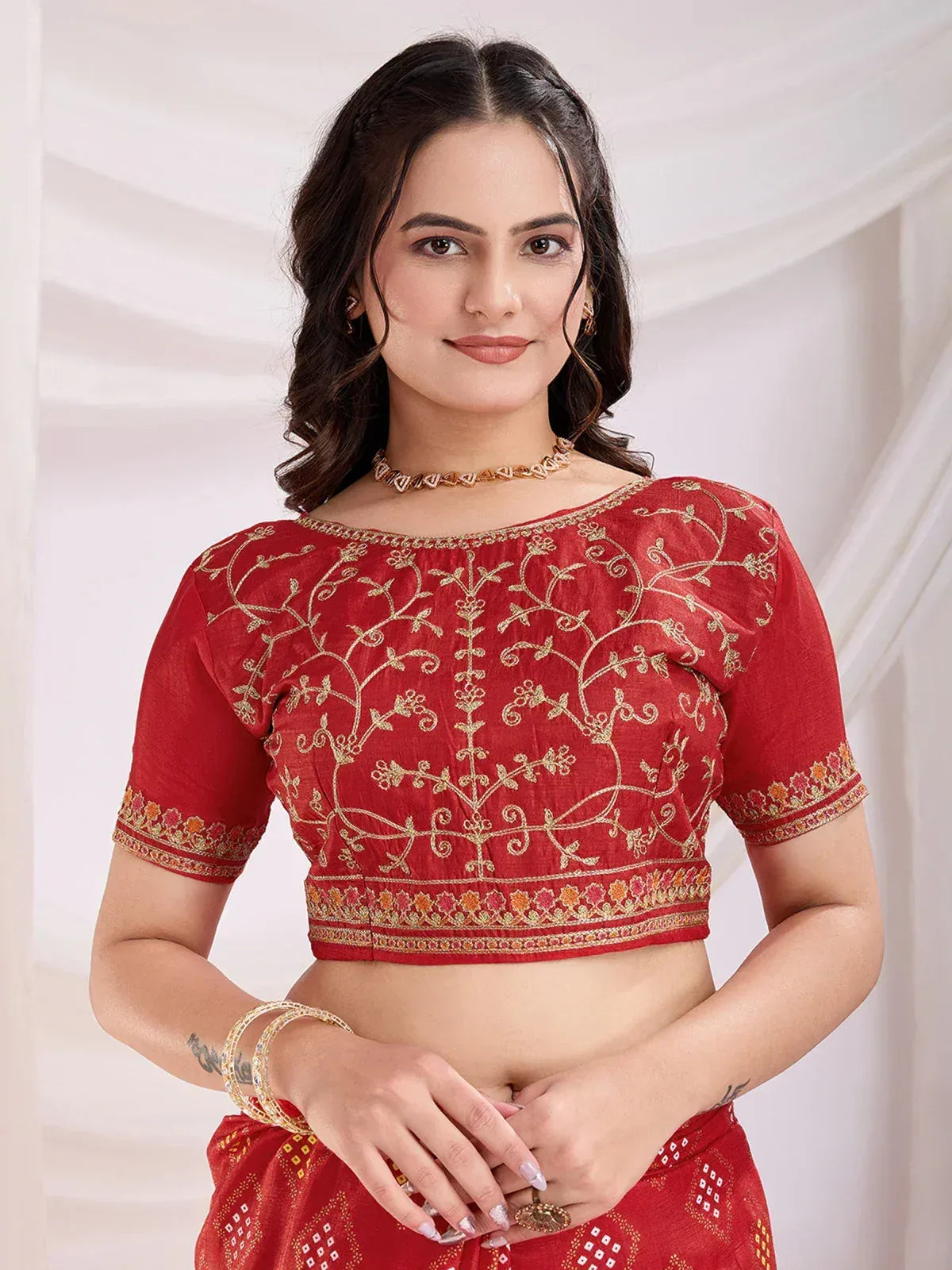 Red embroidered blouse with gold floral design, paired with matching ethnic saree for festive occasions
