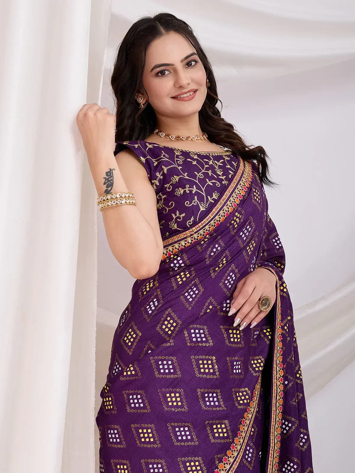 Purple ethnic saree with gold embroidery and mirror work, styled with choker and bangles