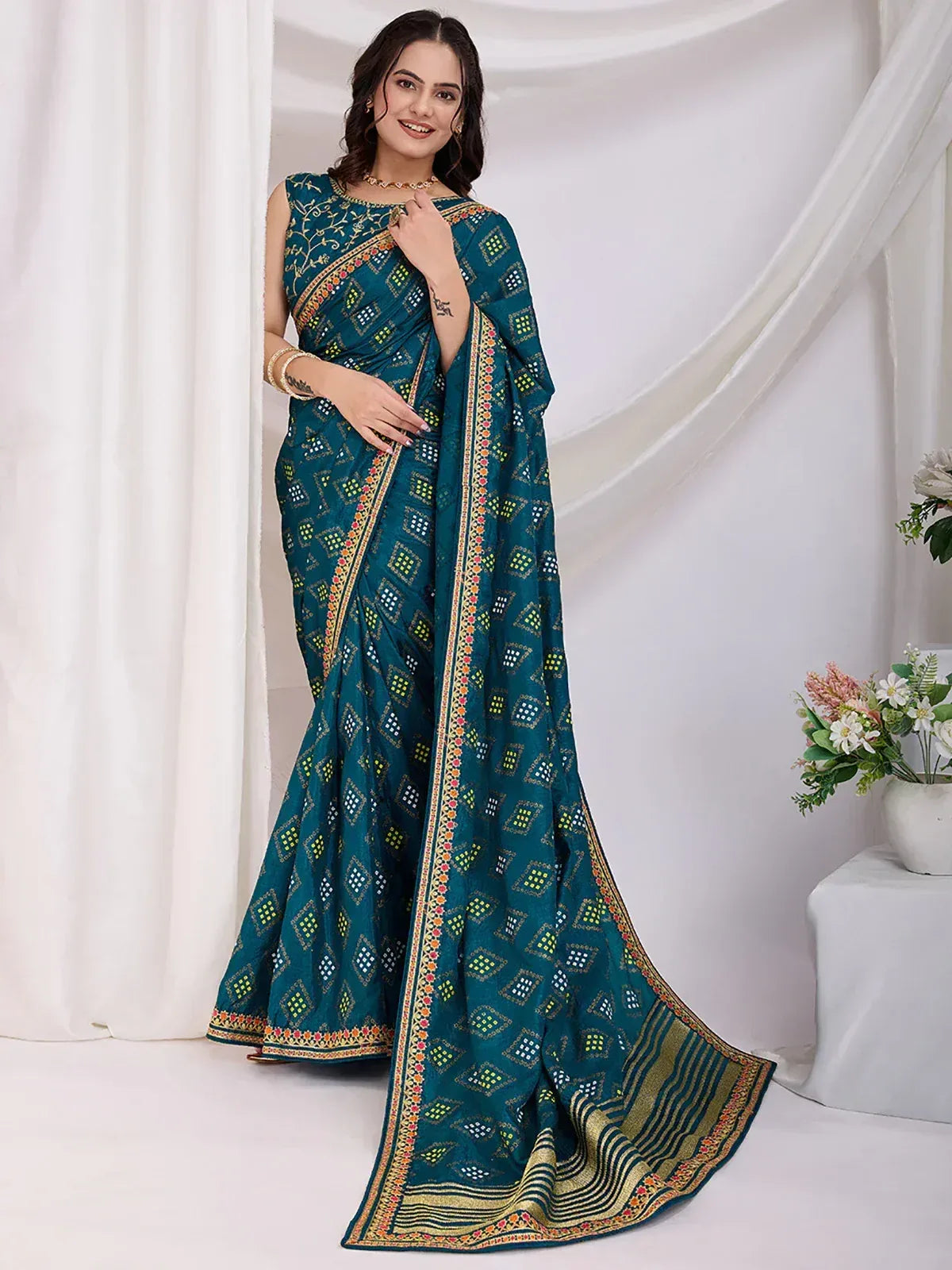 Teal printed saree with geometric pattern and embroidered border, styled with matching blouse for ethnic wear