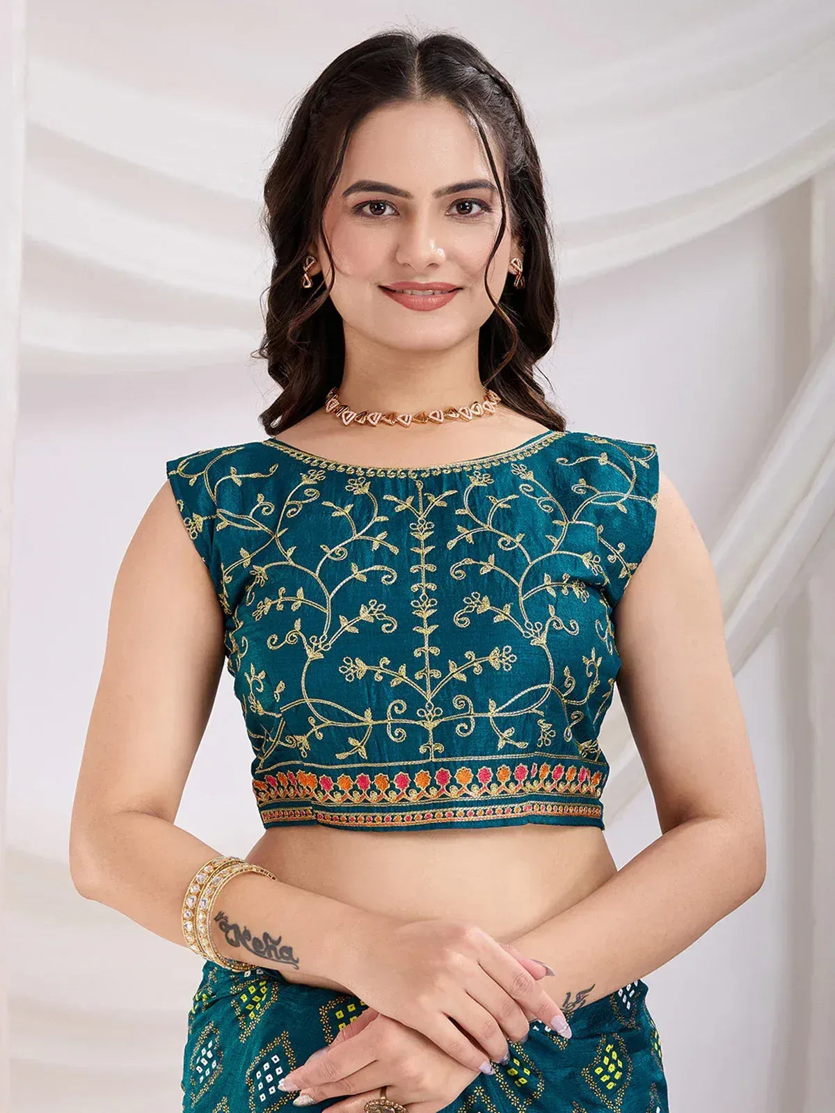 Teal embroidered crop top with gold floral design, paired with matching ethnic skirt for Indian wear