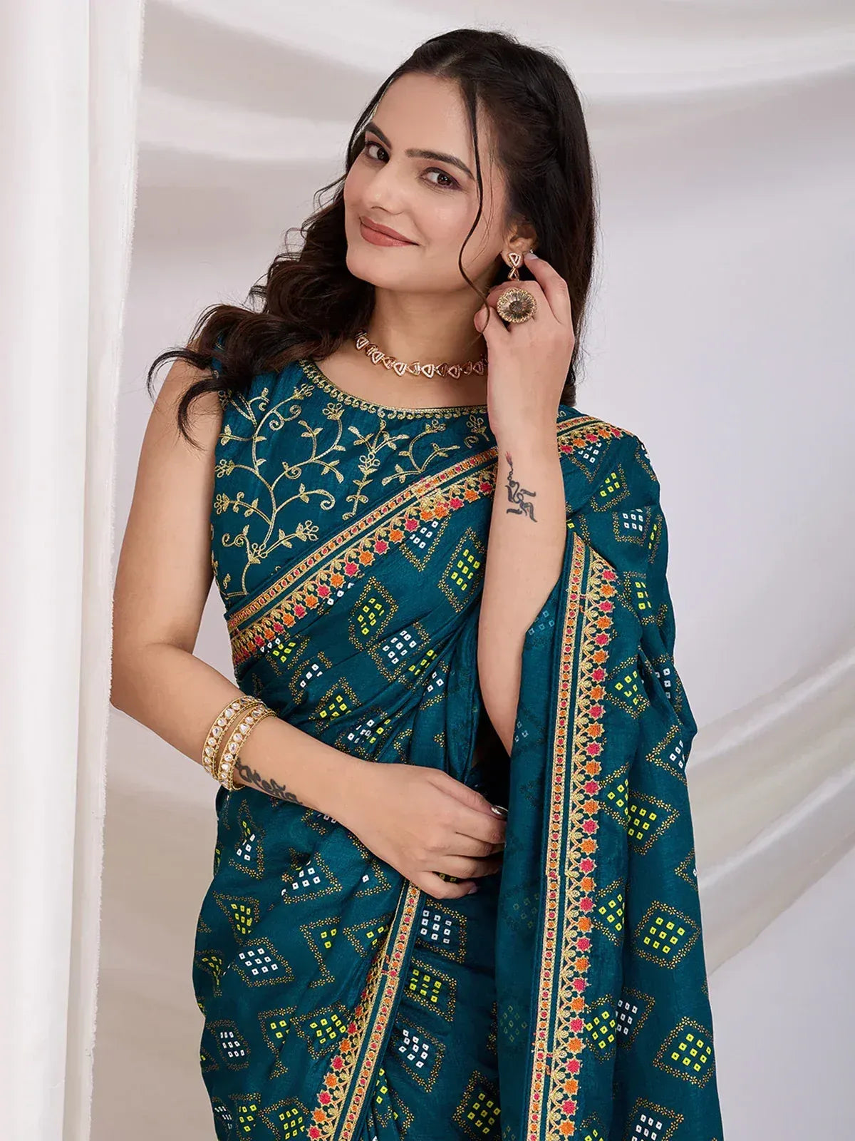 Teal embroidered saree with gold floral and geometric patterns, styled with traditional jewelry for ethnic wear