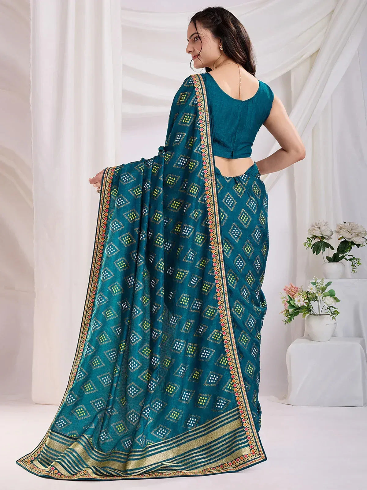 Teal printed saree with geometric pattern and gold border, paired with matching blouse for ethnic wear
