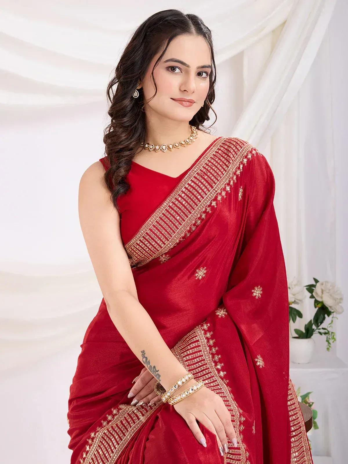 Red embroidered saree with gold border, styled with choker and bangles for ethnic occasions