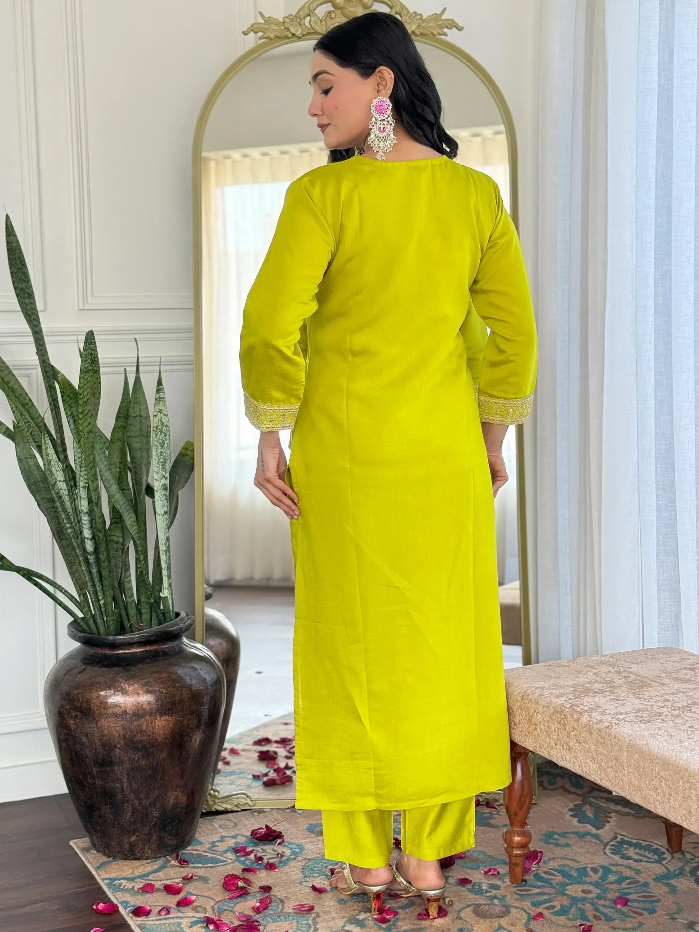 Bright yellow ethnic kurta with gold trim, paired with matching pants, worn by woman near mirror