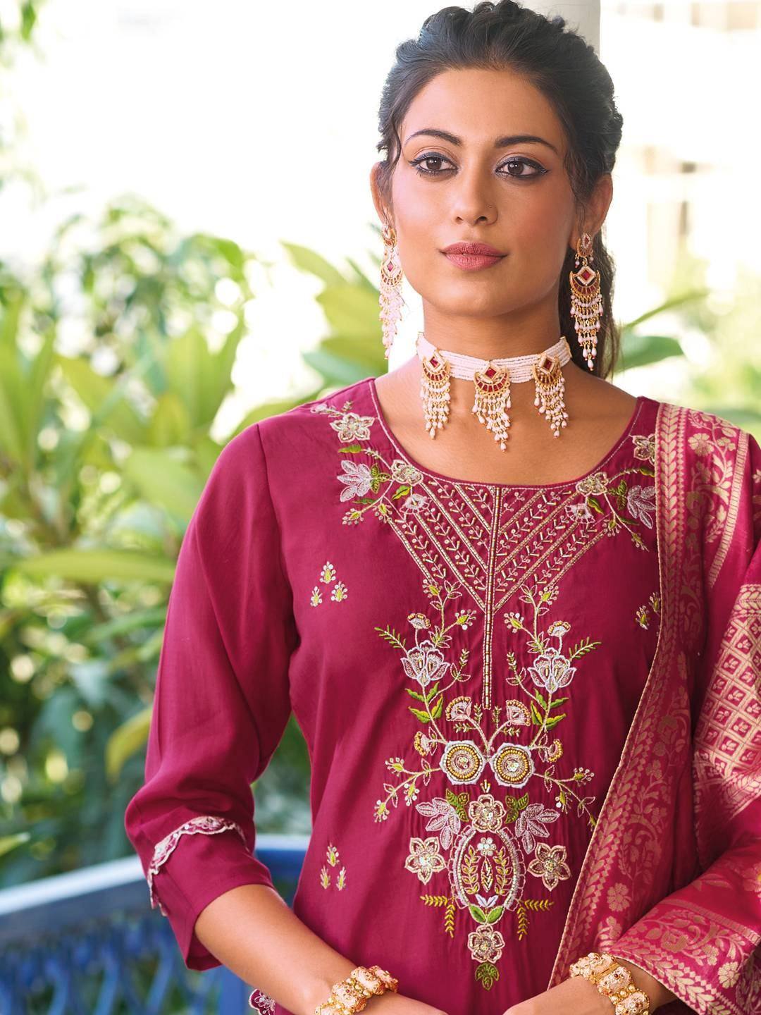 Woman in maroon embroidered salwar kameez with floral detailing and gold jewelry