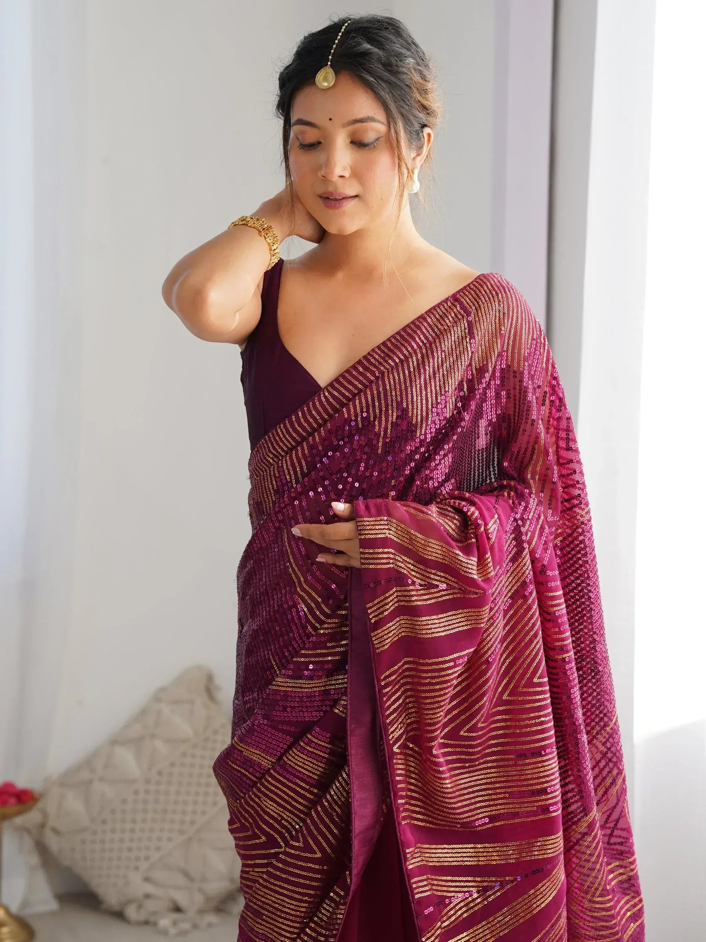 Woman in maroon sequin saree with gold stripes, ethnic Indian wear for festive occasions