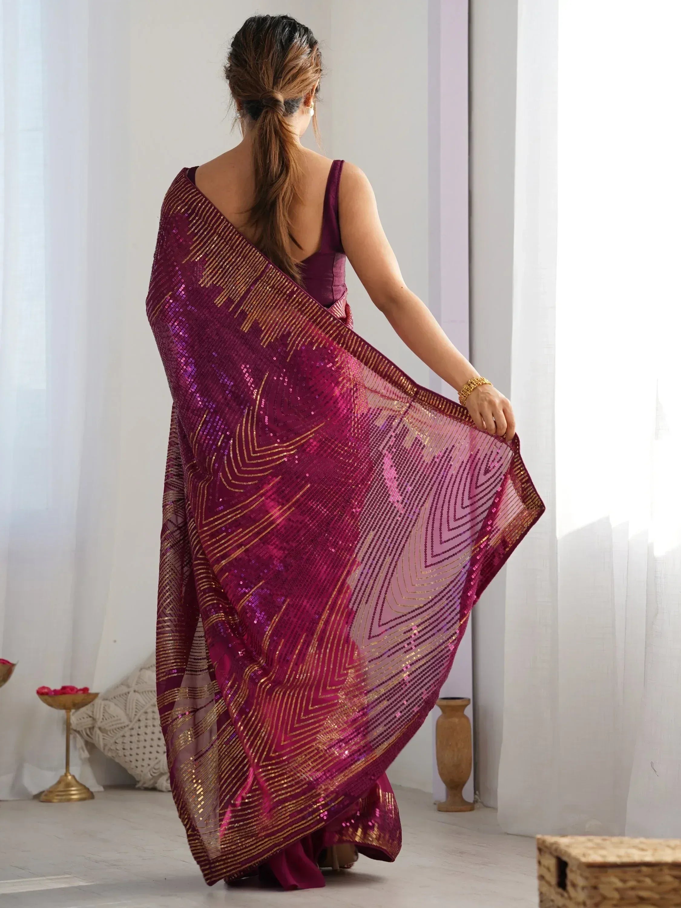 Woman in back view wearing maroon sequin saree with gold geometric patterns, ethnic Indian wear