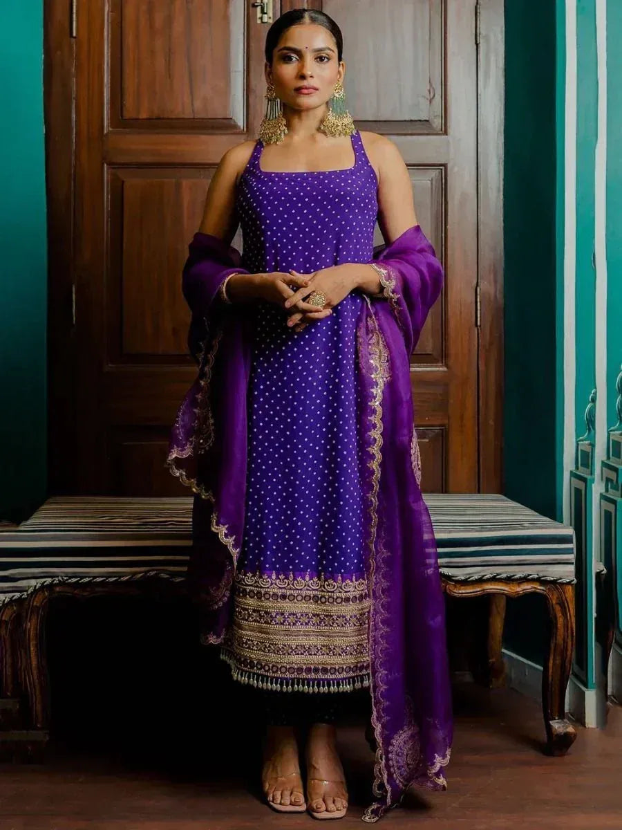 Purple polka dot ethnic gown with gold embroidery and matching dupatta, styled for Indian occasions