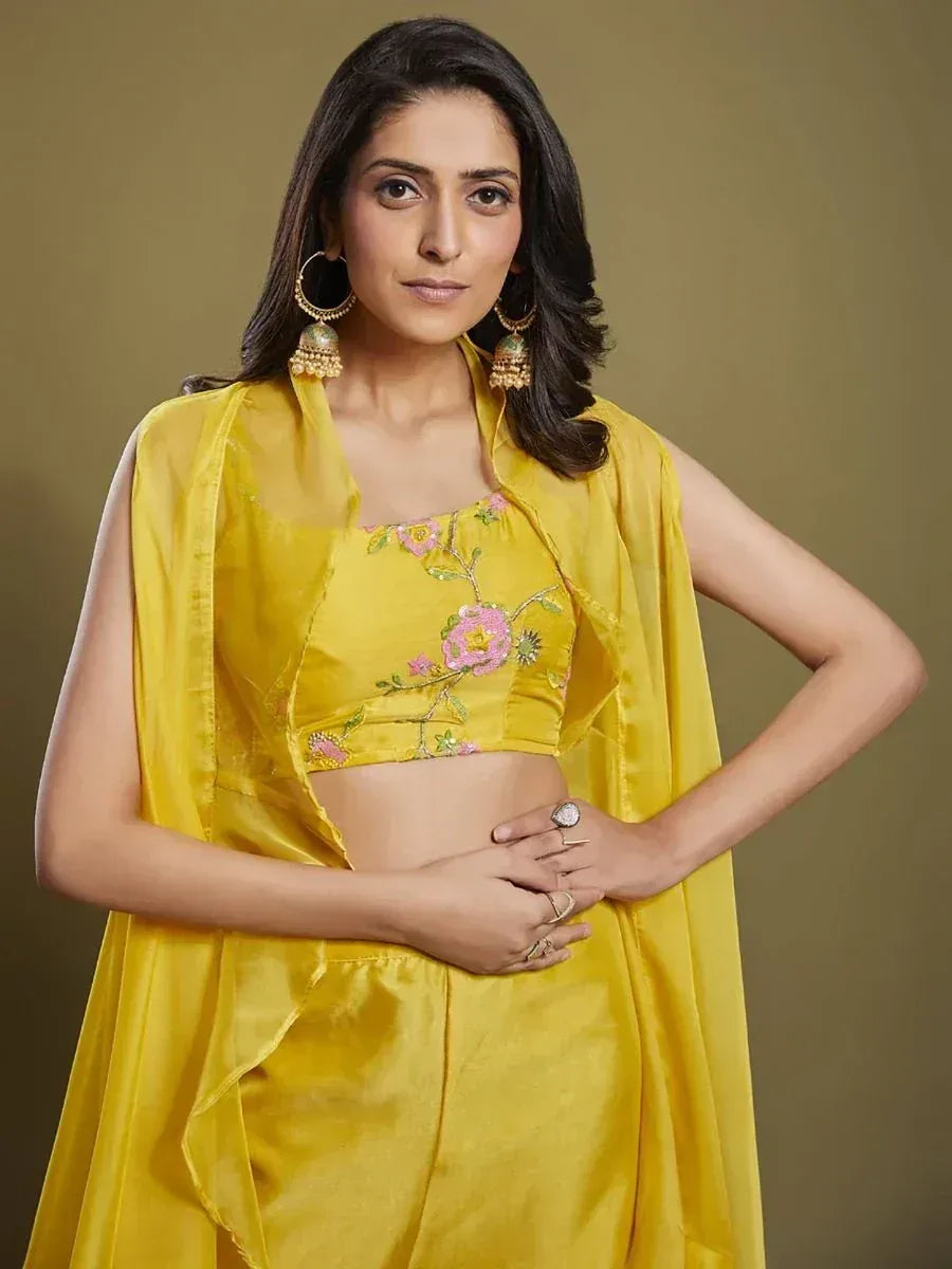 Woman in yellow designer lehenga choli with floral embroidery, traditional earrings
