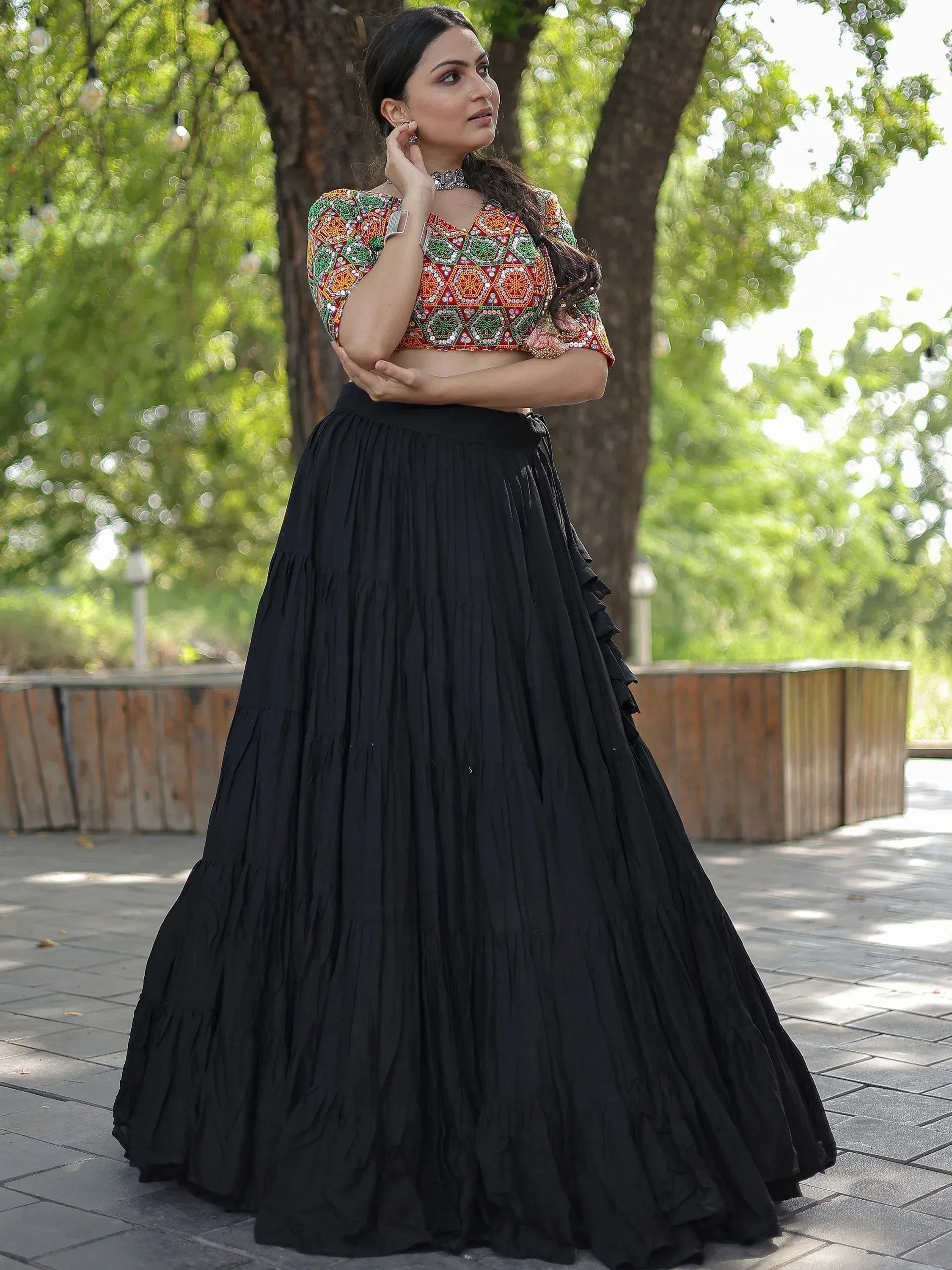 Woman in colorful embroidered crop top and black pleated lehenga skirt, ethnic Indian wear