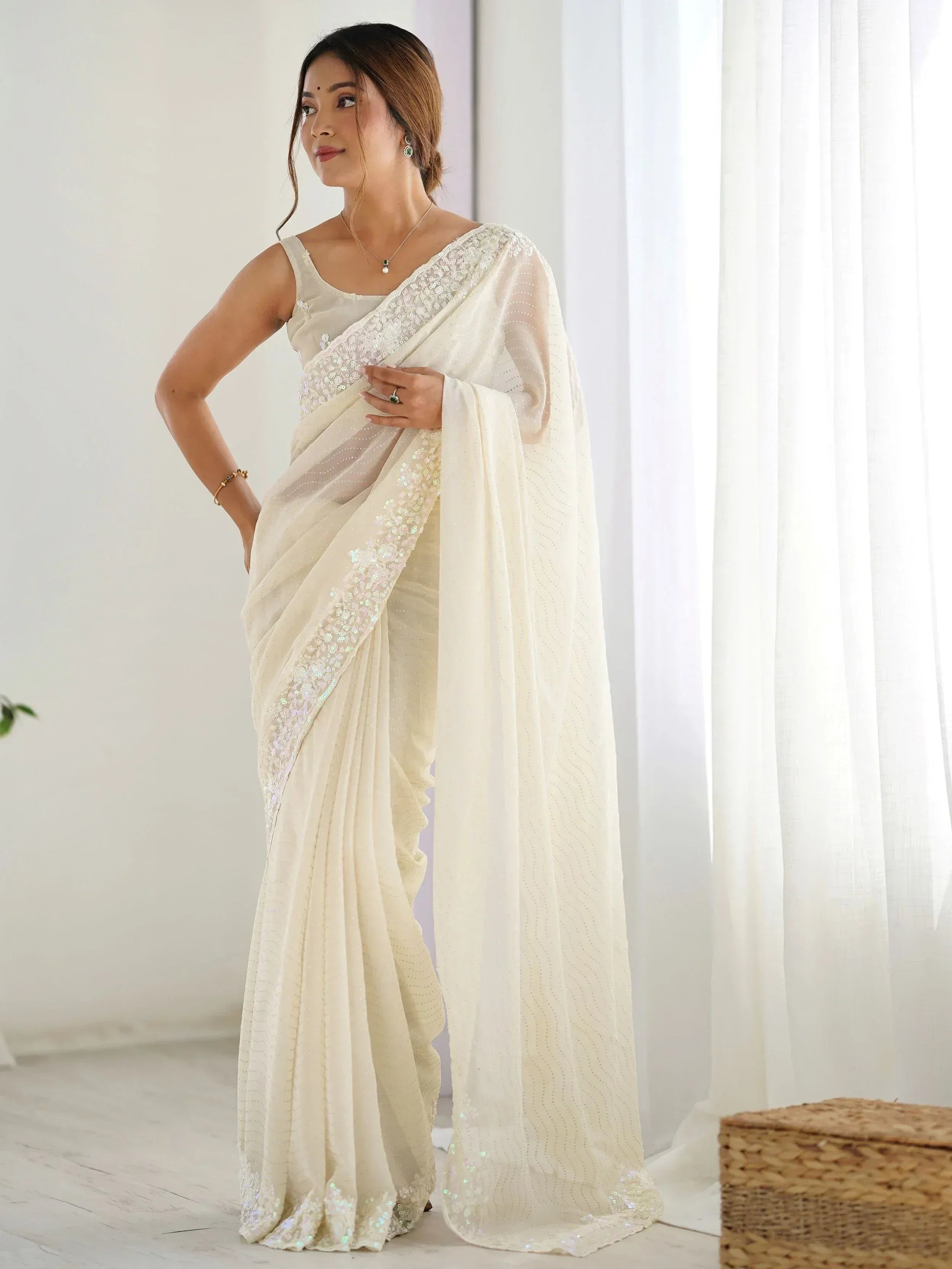 Elegant ivory saree with sequin border and sleeveless blouse, perfect for Indian ethnic occasions