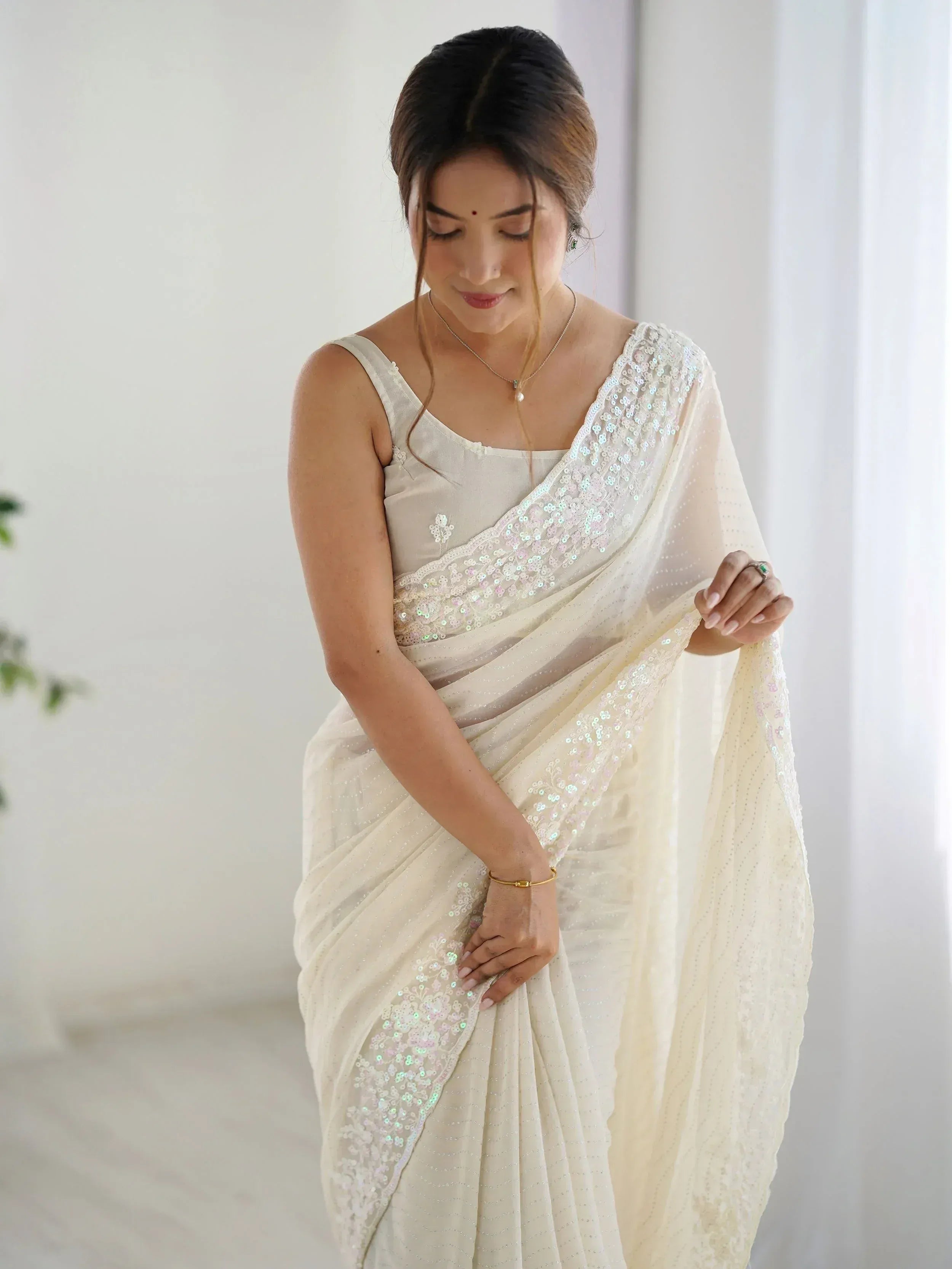 Elegant off-white saree with sequin embroidery, perfect for Indian ethnic occasions and weddings.