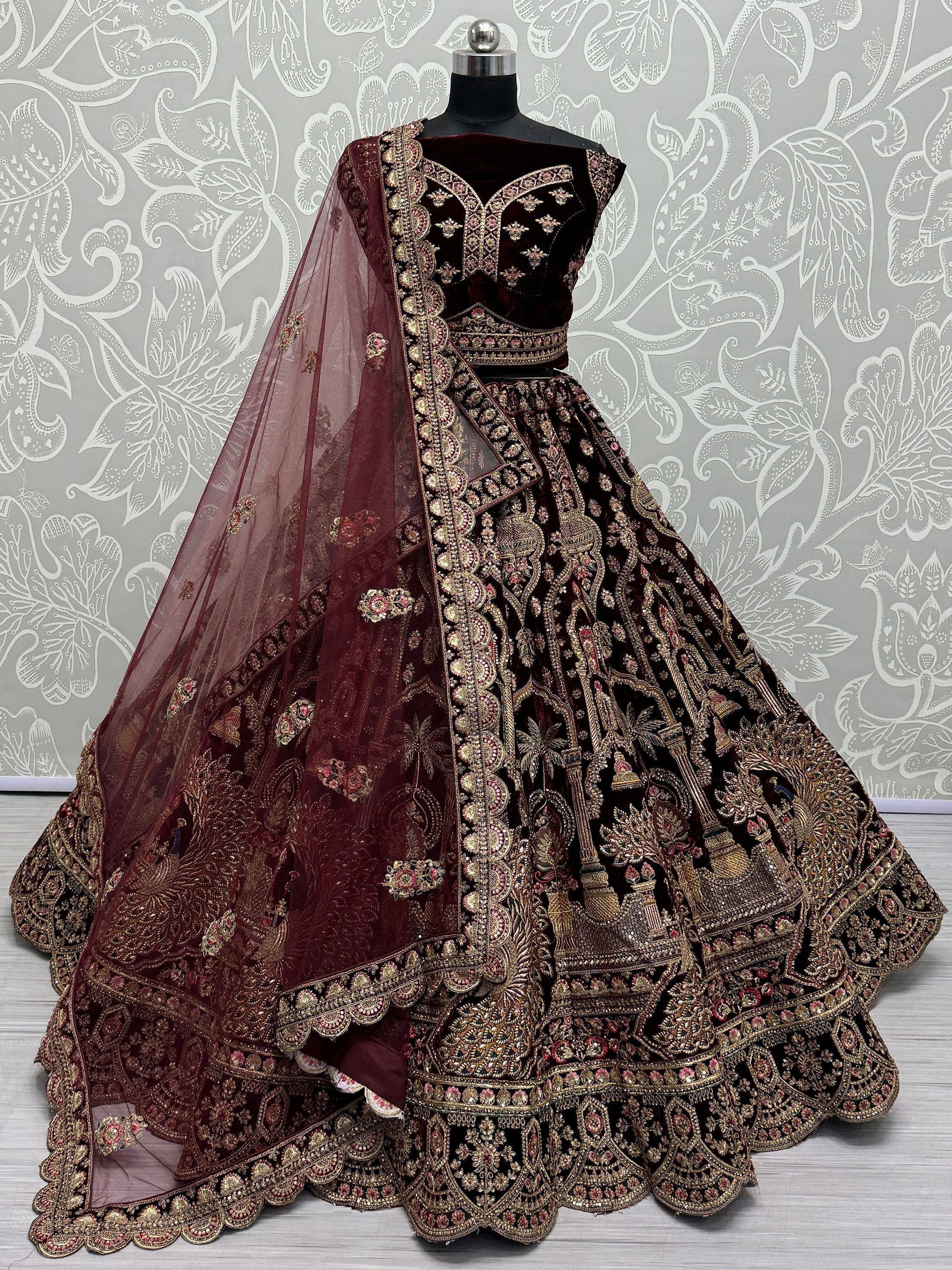 Burgundy velvet lehenga choli with heavy gold embroidery and matching dupatta, ideal for Indian weddings and festive occasions.