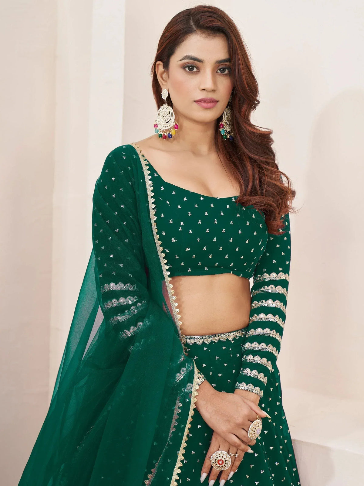 Emerald green embroidered lehenga choli with sequin work and matching dupatta, styled with statement earrings