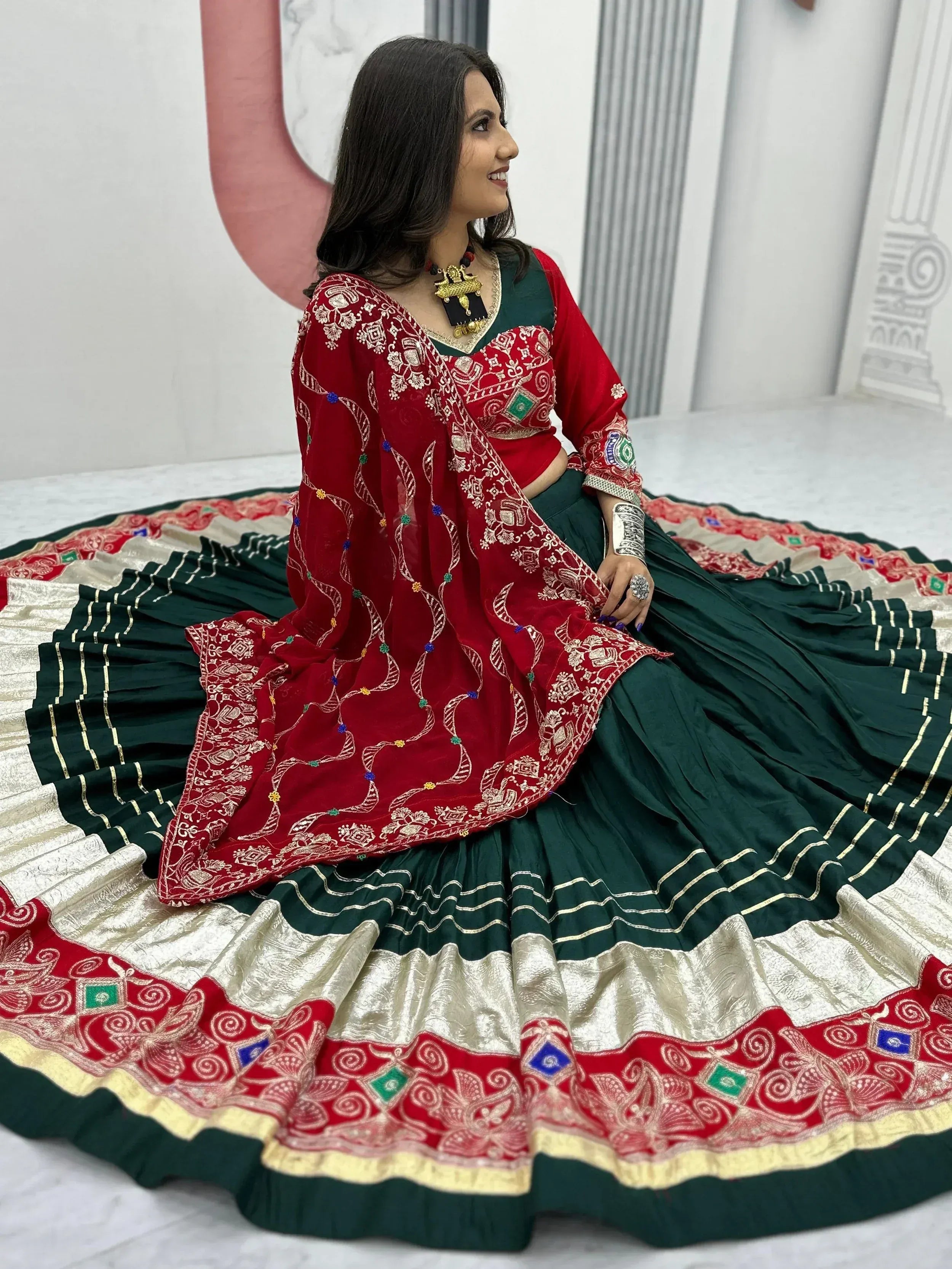 Woman in red and green embroidered lehenga choli with dupatta, traditional Indian ethnic wear