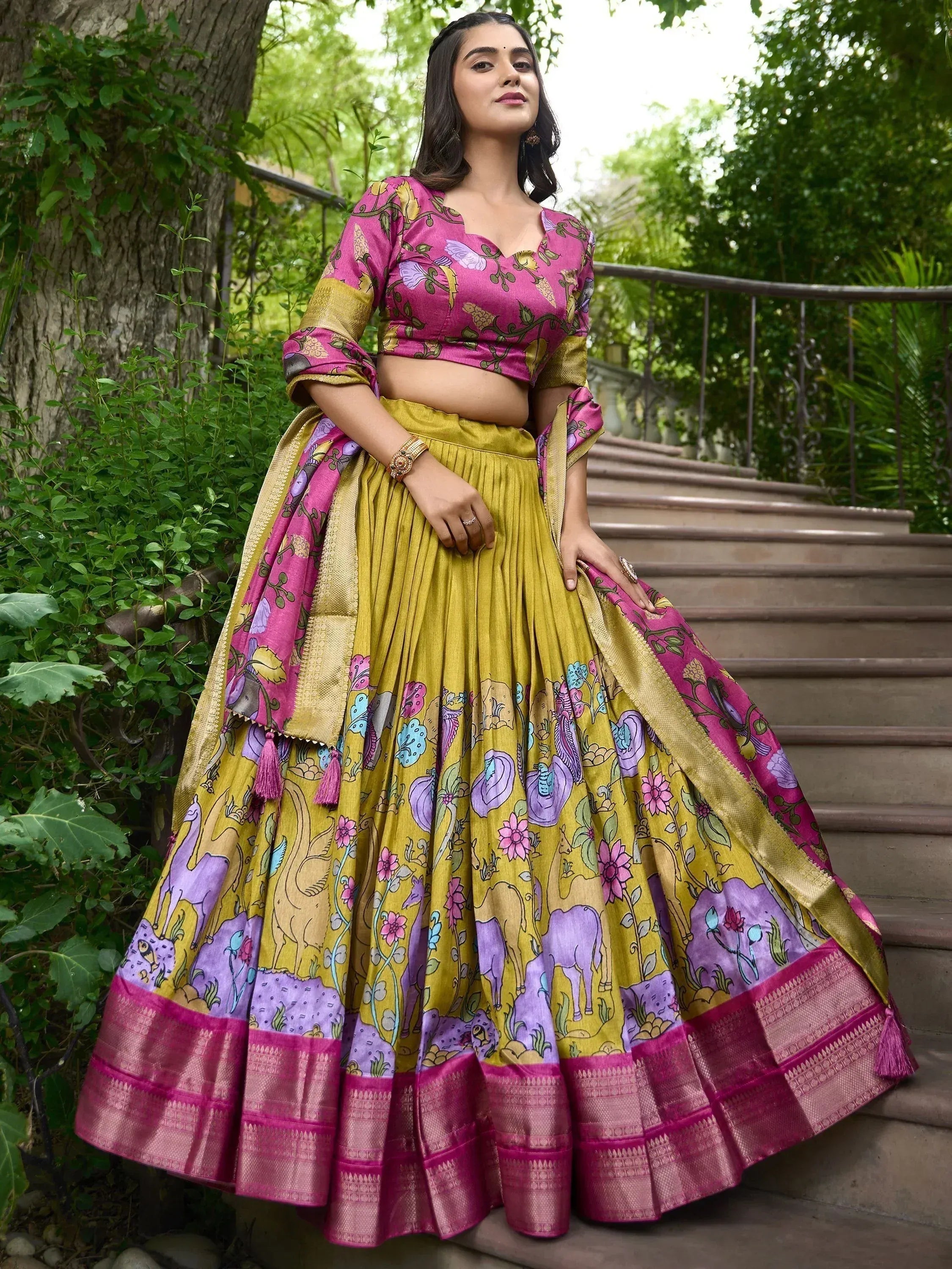 Woman in vibrant pink and yellow printed lehenga choli with floral and animal motifs, perfect for ethnic occasions