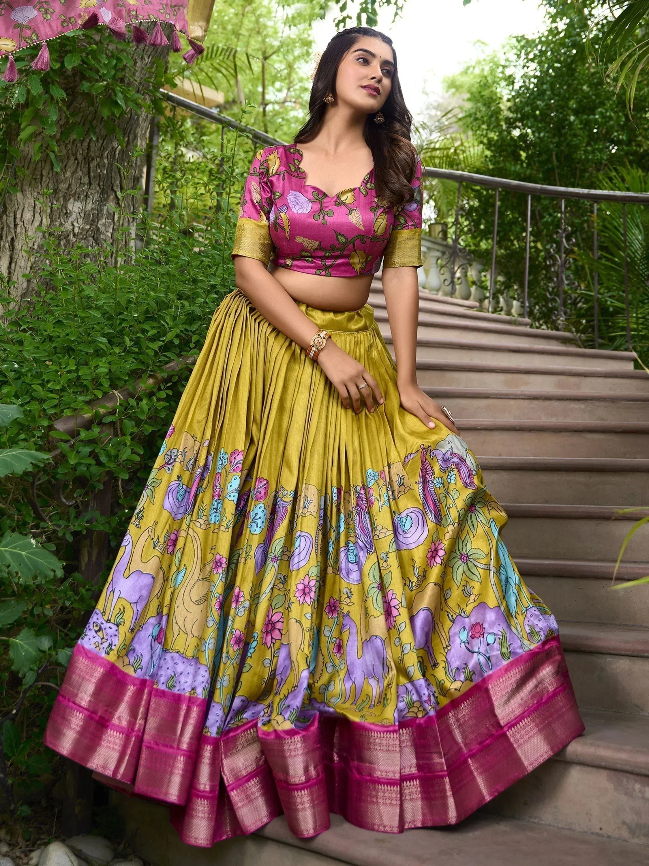 Woman in vibrant yellow and pink printed lehenga choli with floral and animal motifs, perfect for Indian ethnic occasions.