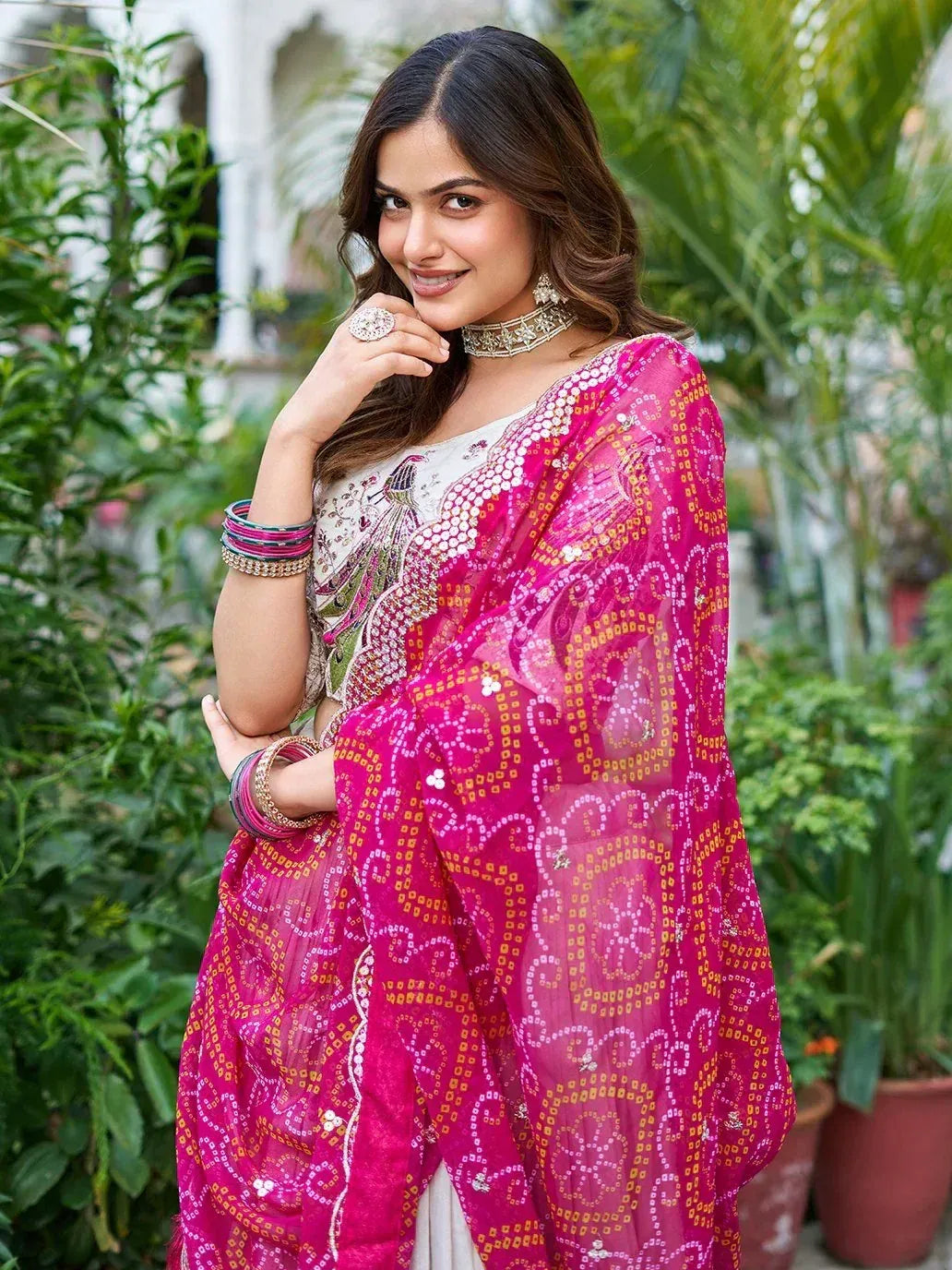 Woman in vibrant pink embroidered saree with gold patterns, styled with choker and bangles, perfect for Indian ethnic occasions.
