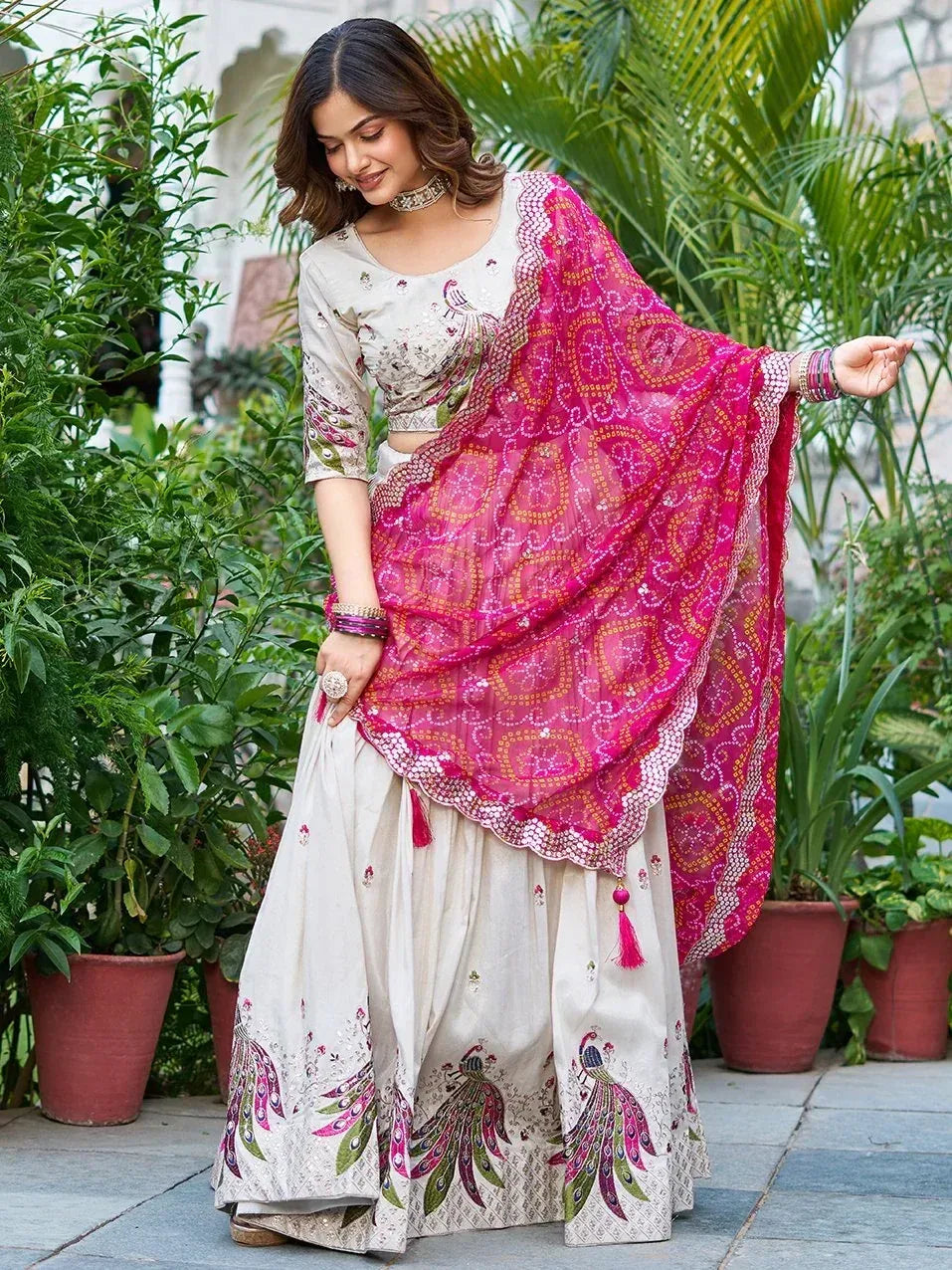 Elegant cream lehenga choli with peacock embroidery and vibrant pink dupatta, perfect for Indian ethnic occasions